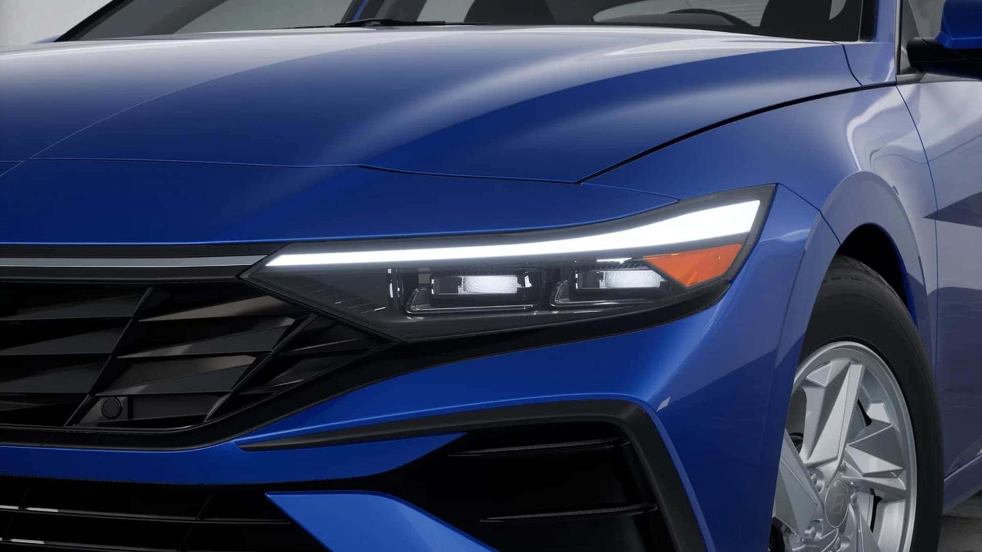 Close up of 2026 Hyundai Elantra front headlight showing LED headlamp design, daytime running light strip, and front grille styling