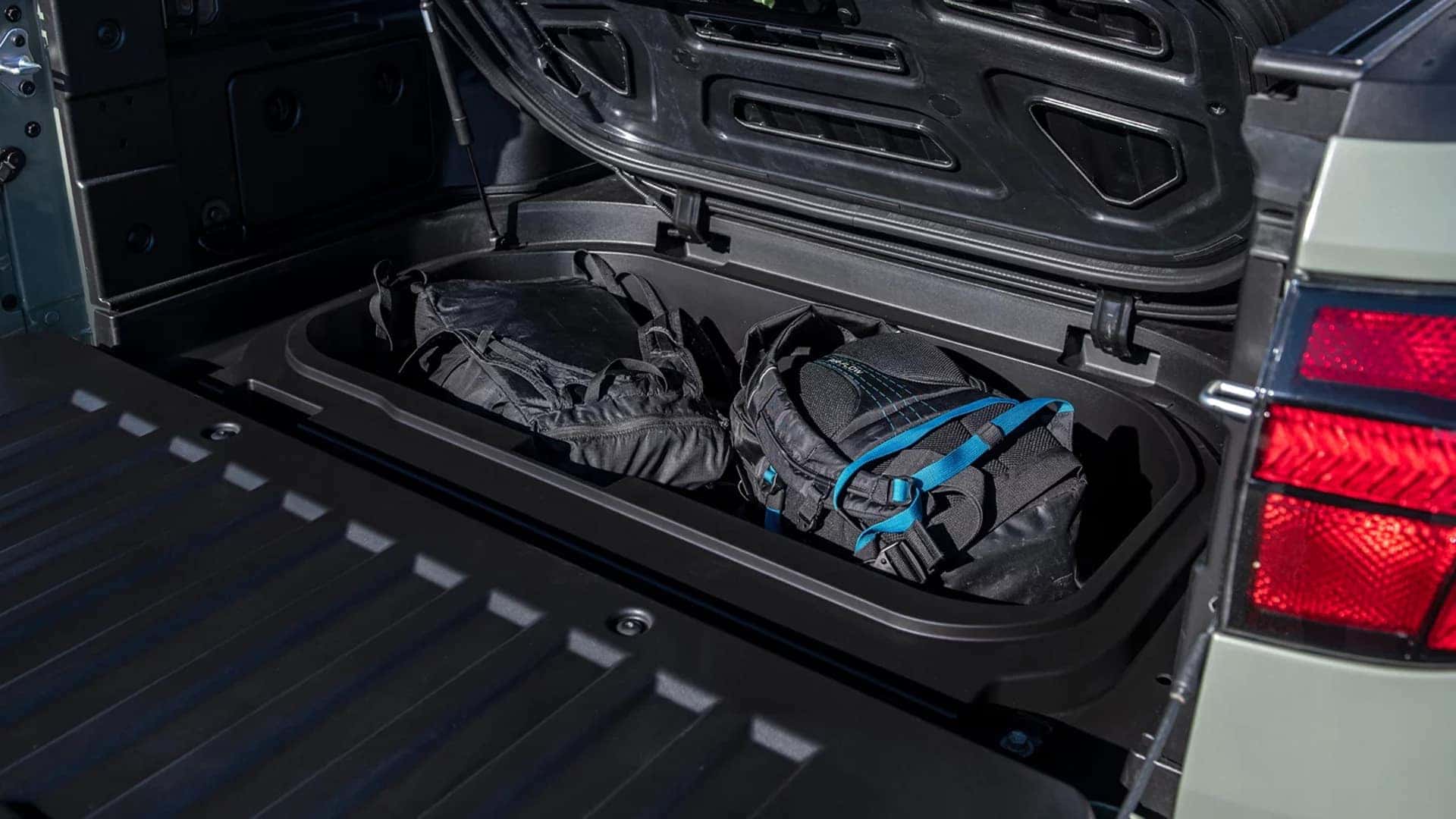 Under bed storage compartment in the 2026 Hyundai Santa Cruz holding secured backpacks and outdoor equipment