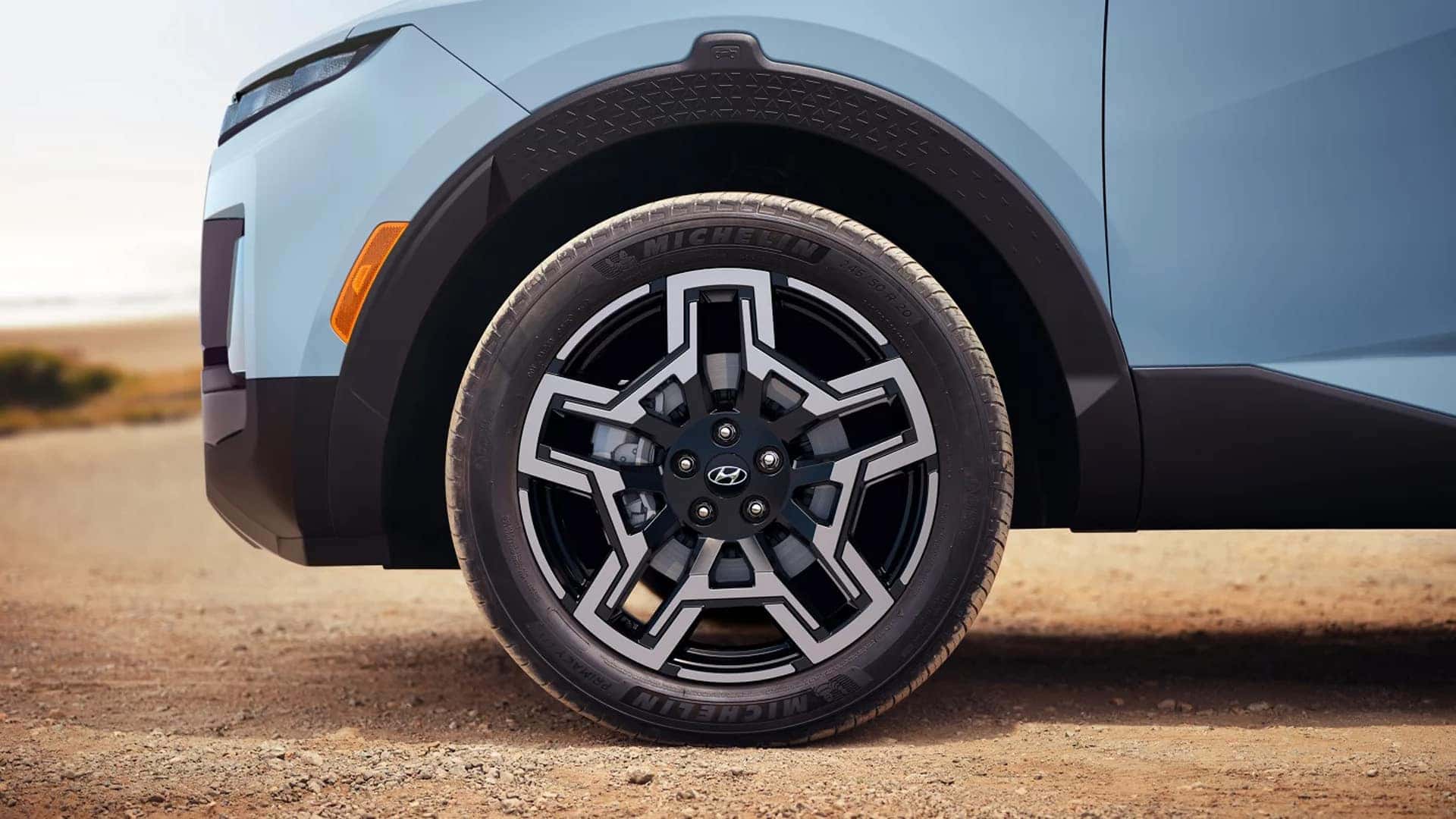 Close up of a 2026 Hyundai Santa Cruz front wheel showing two tone alloy wheel design, tire, and black fender cladding.