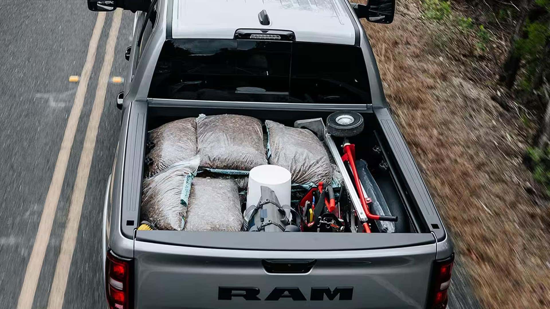 Overhead view of a 2026 Ram 1500 bed carrying secured cargo while driving on a rural road