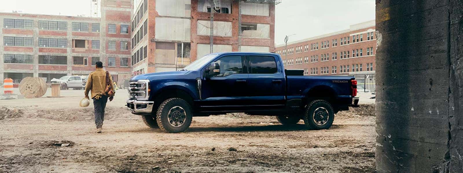 2026 Ford F-250 Super Duty Tremor parked at a construction site, showing crew cab body style, off-road tires, and bold front grille design.