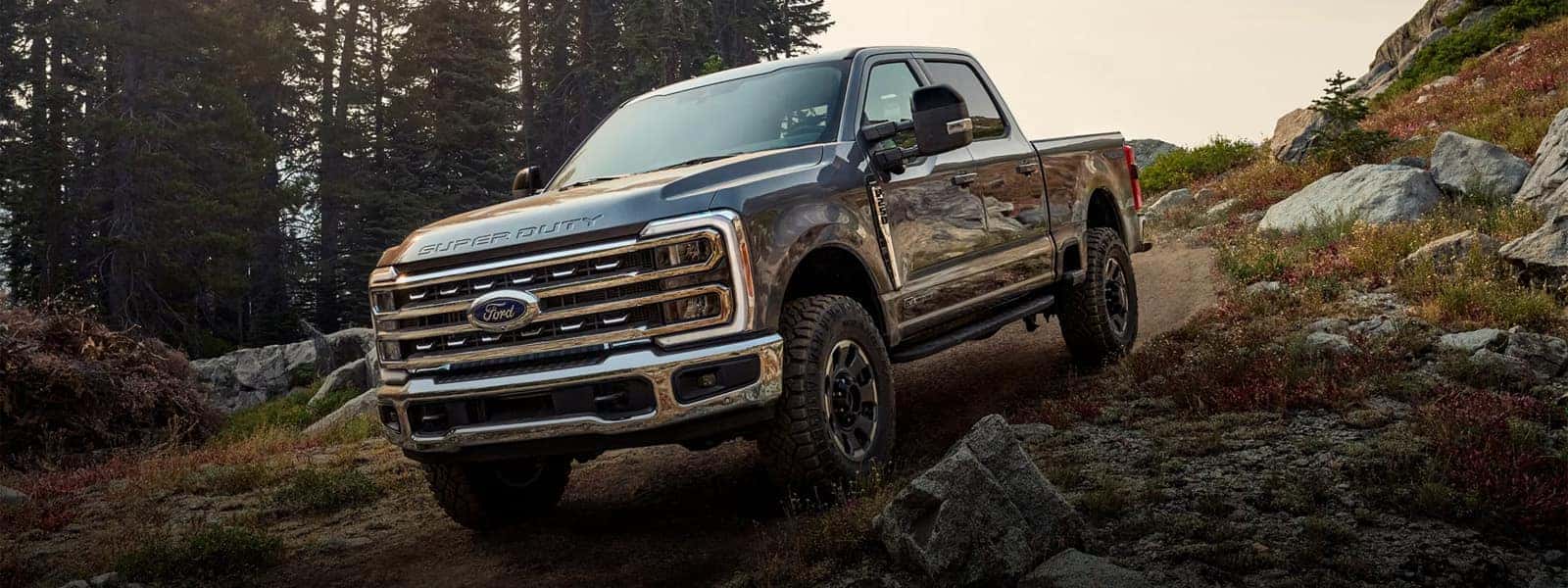 2026 Ford F-250 Super Duty driving on a rocky trail in the mountains, front three quarter view