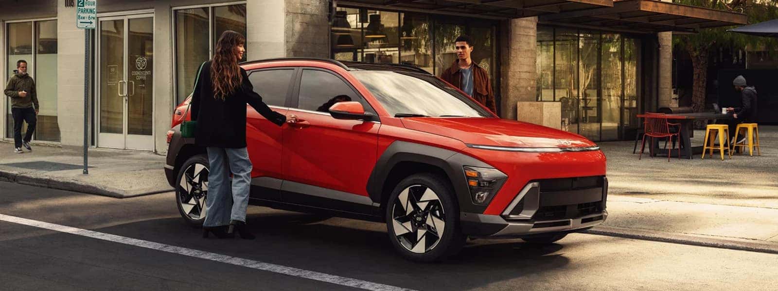 2026 Hyundai Kona parked along a city street with people nearby, showcasing compact SUV design, bold exterior styling, and everyday urban usability