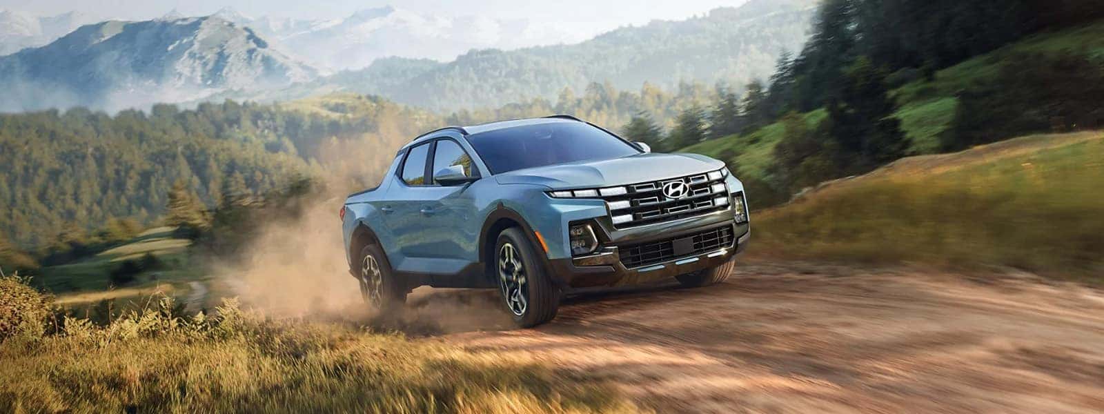 2026 Hyundai Santa Cruz driving on a dirt road in a mountain landscape, front three quarter view