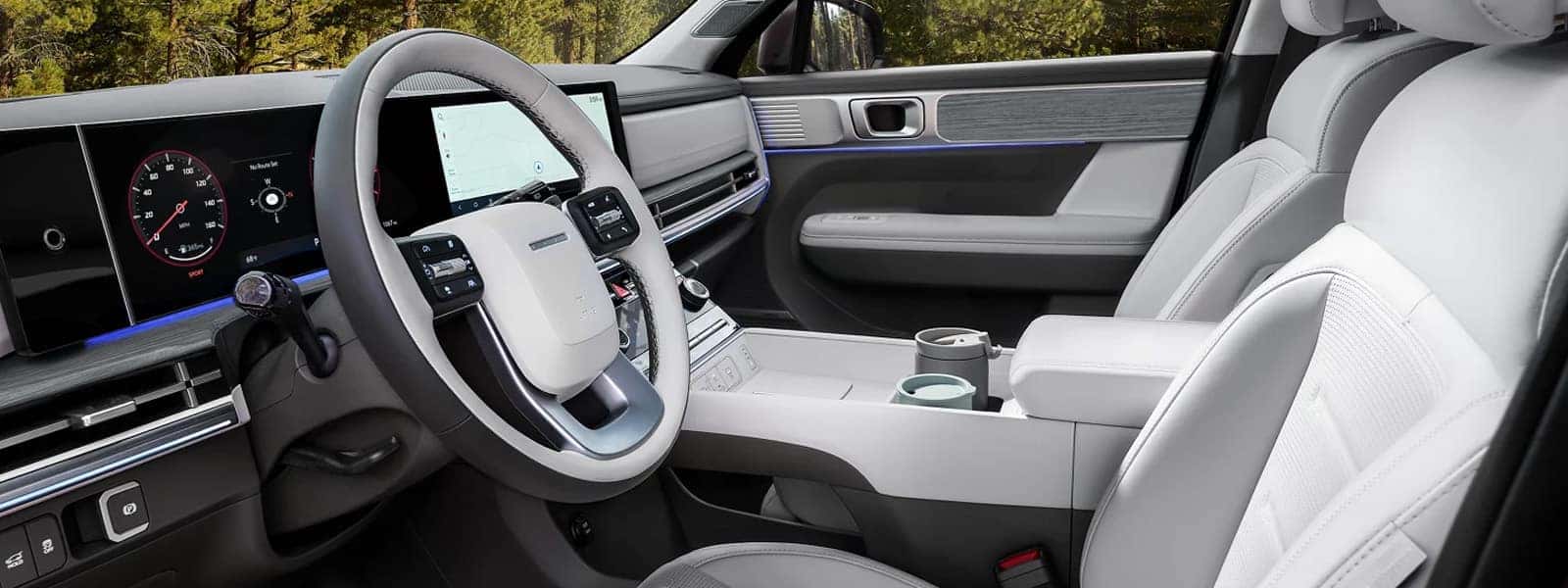 Front interior view of the 2026 Hyundai Santa Fe showing the steering wheel, wide dashboard displays, center console, and light colored seating