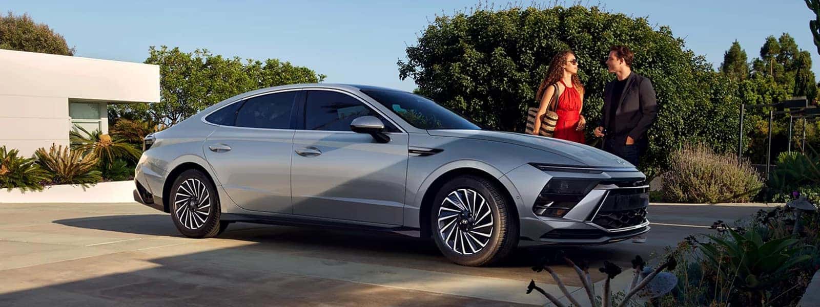 2026 Hyundai Sonata parked in a modern residential setting, showcasing sleek midsize sedan styling, low profile stance, and contemporary exterior design