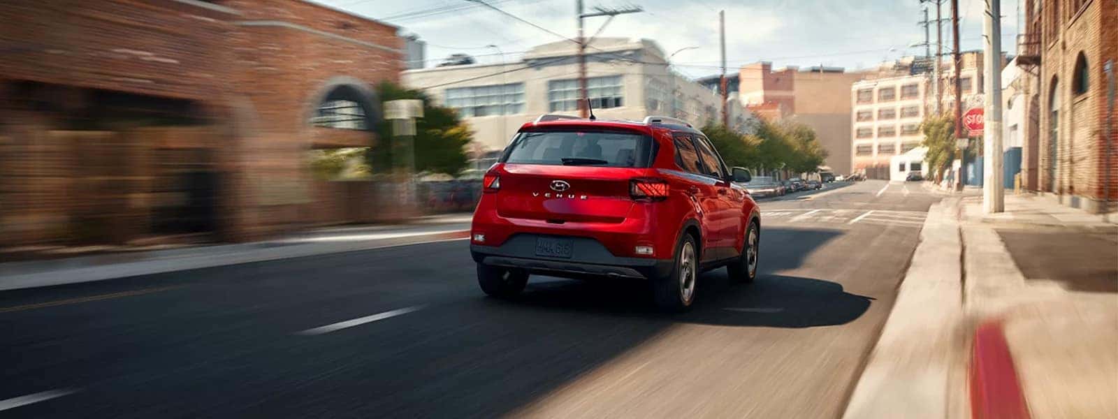 2026 Hyundai Venue driving through a city street, rear three quarter view