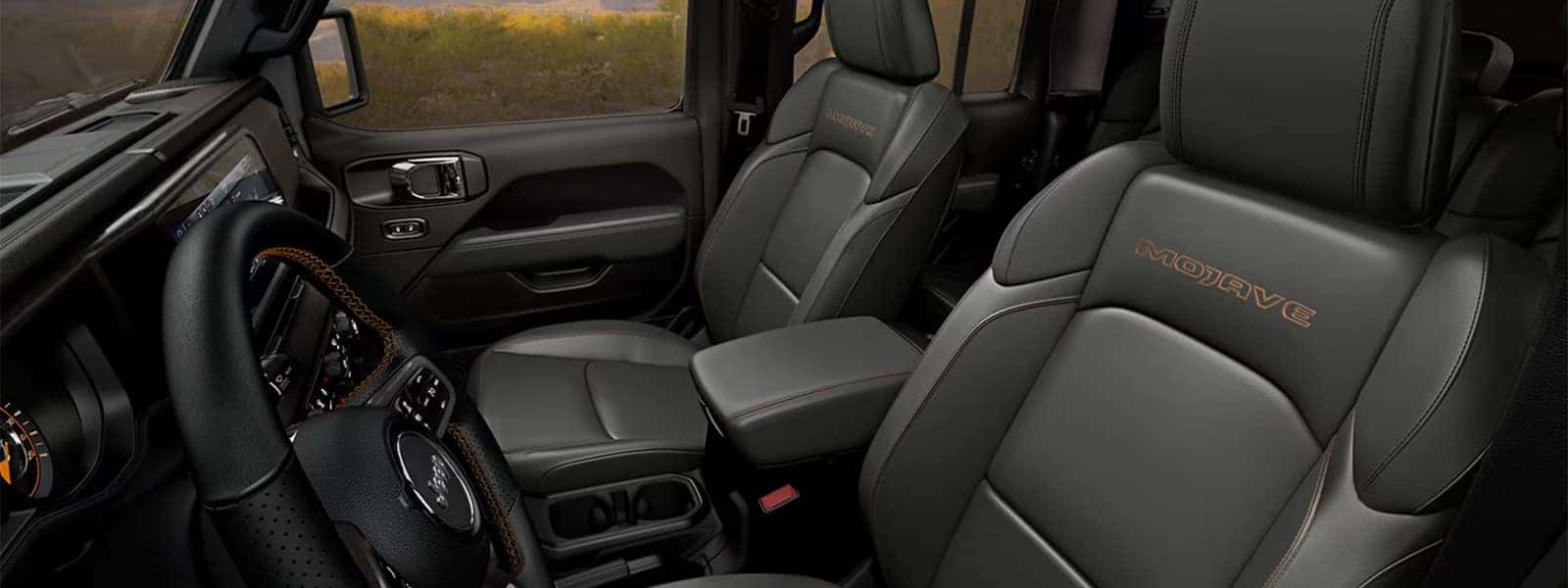 Front seats and cockpit of the 2026 Jeep Gladiator Mojave interior with center console and touchscreen