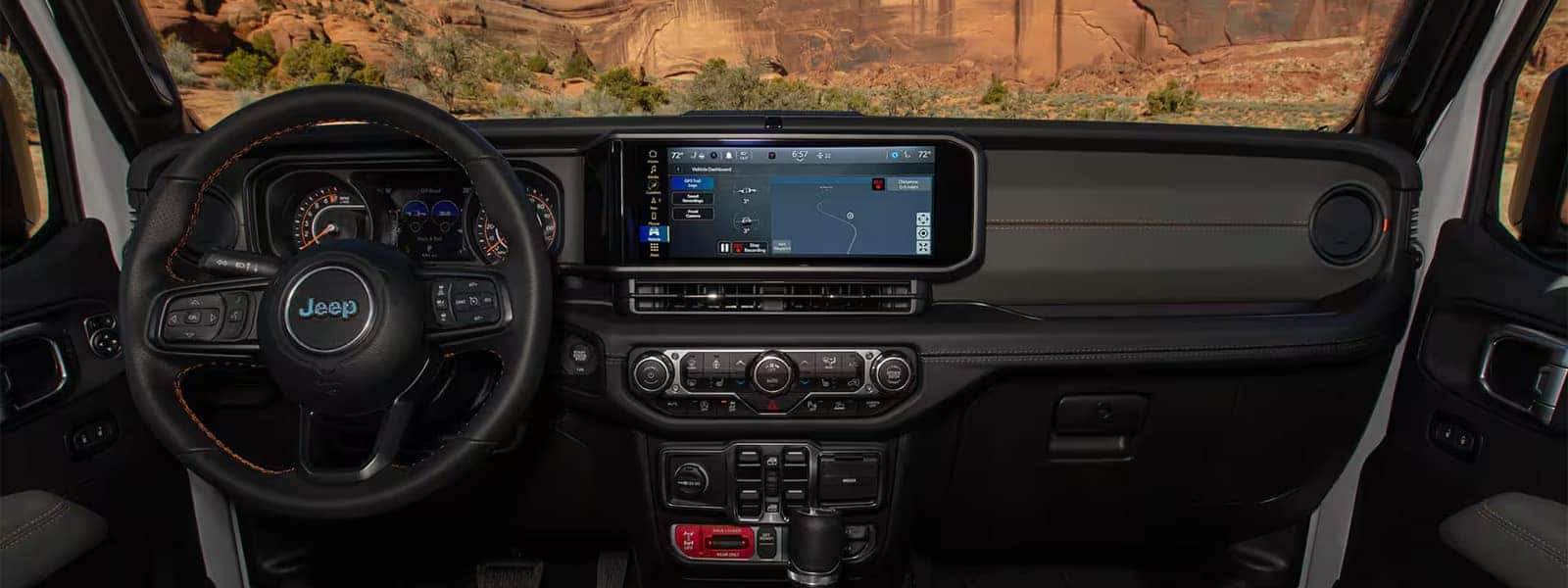 Interior dashboard view of the 2026 Jeep Gladiator featuring the 12.3-inch Uconnect touchscreen, analog gauge cluster, and rugged cabin layout