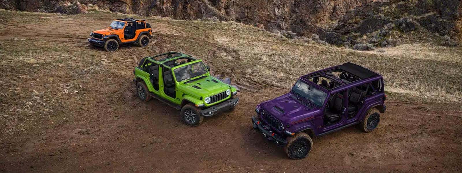 Three 2026 Jeep Wrangler SUVs on a rocky dirt trail, shown from above
