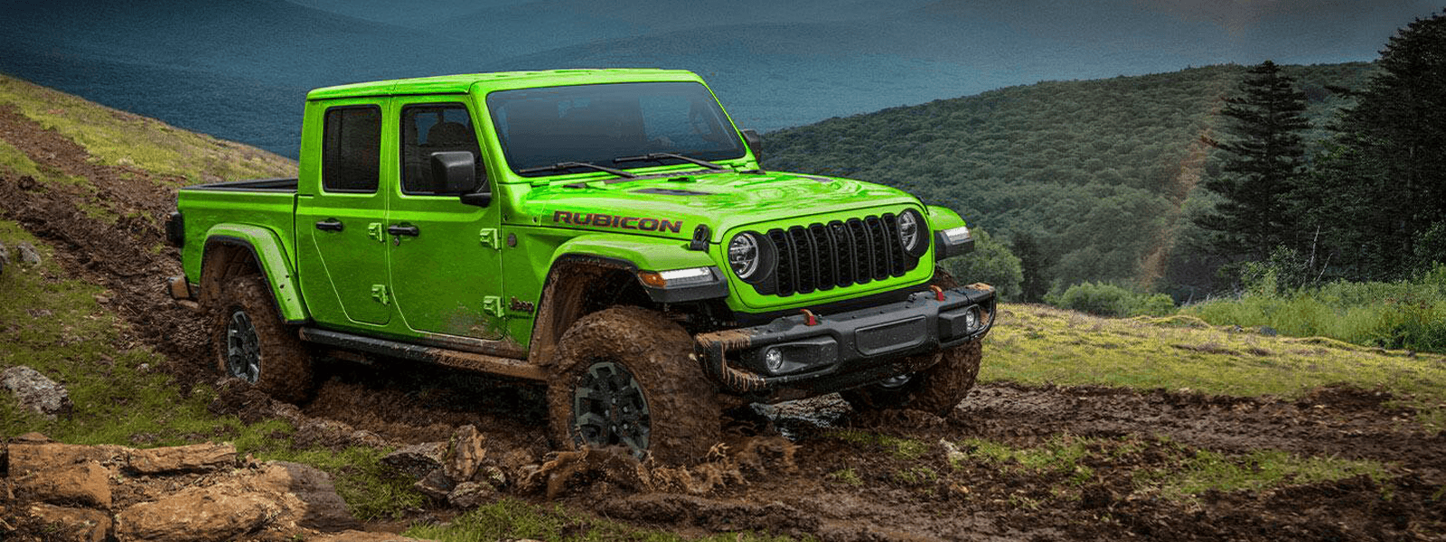 2026 Jeep Gladiator driving on a muddy mountain trail, front three quarter view