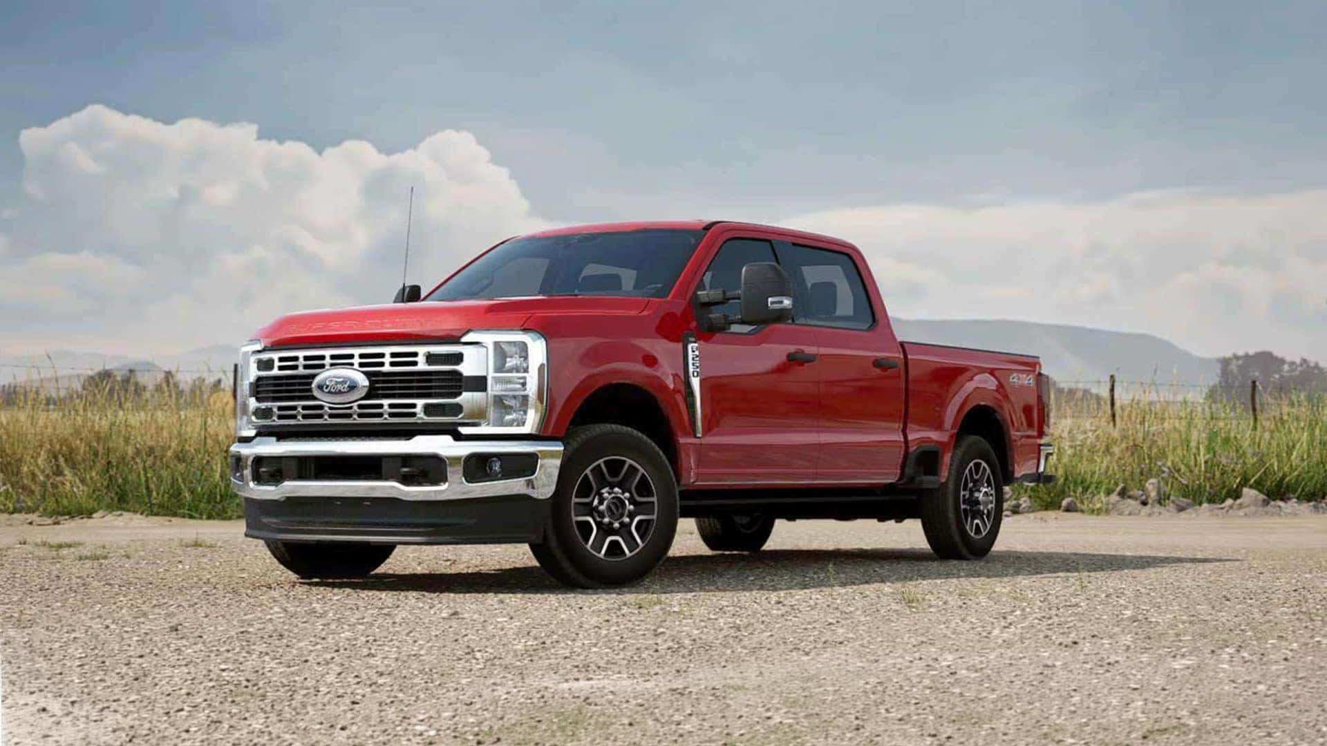 Red 2026 Ford F-250 Super Duty parked on gravel road, highlighting chrome grille, crew cab configuration, and heavy duty truck stance.