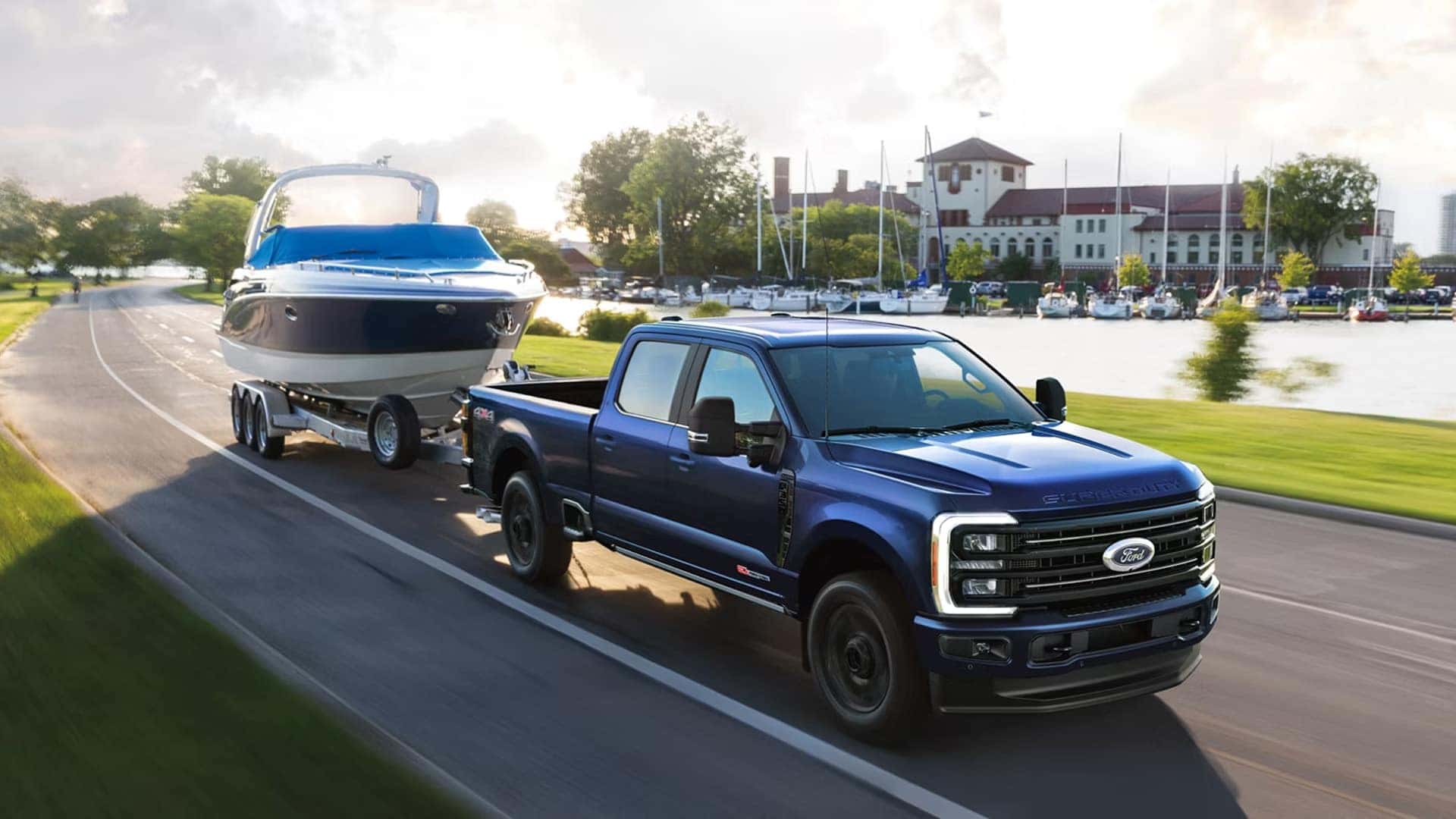 2026 Ford F-250 Super Duty towing a large boat on a multi-axle trailer near a waterfront marina