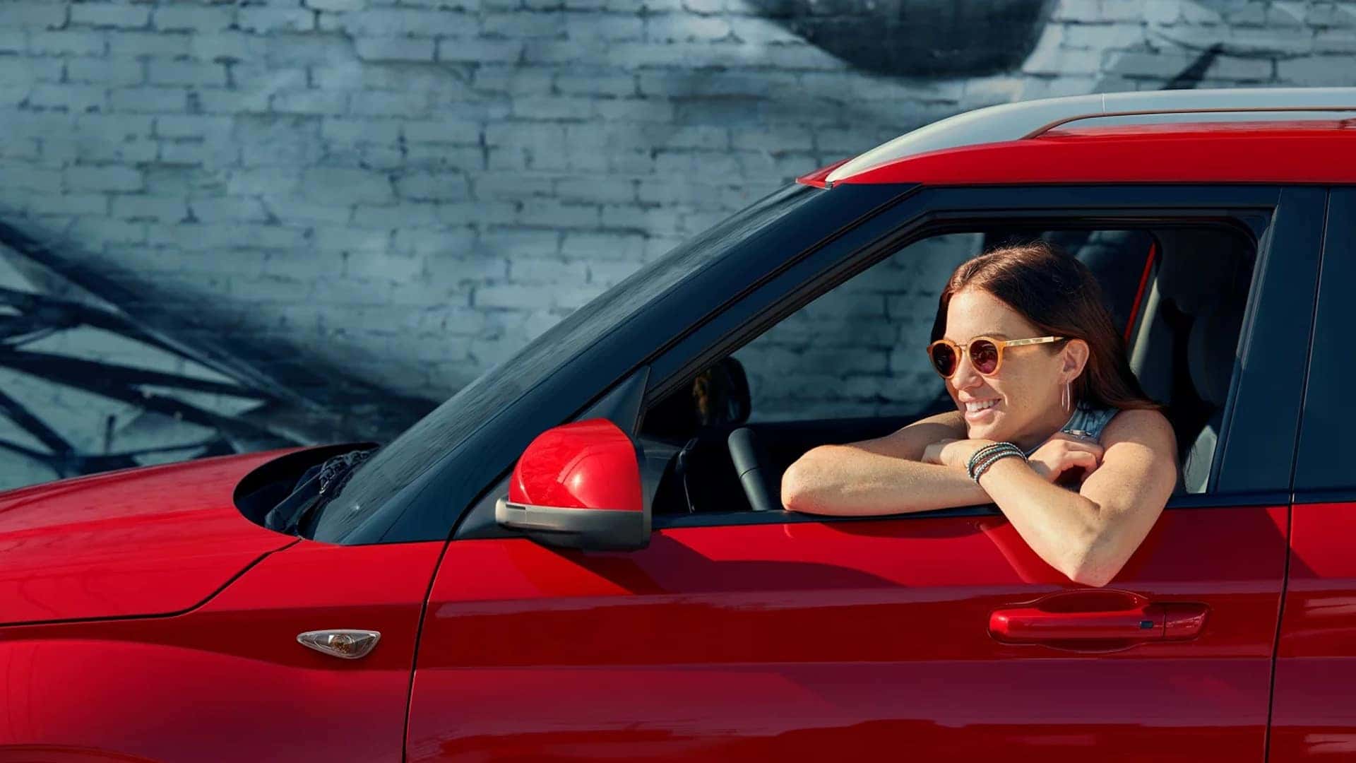 Driver smiling inside a red 2026 Hyundai Venue, highlighting urban-friendly size and everyday drivability.
