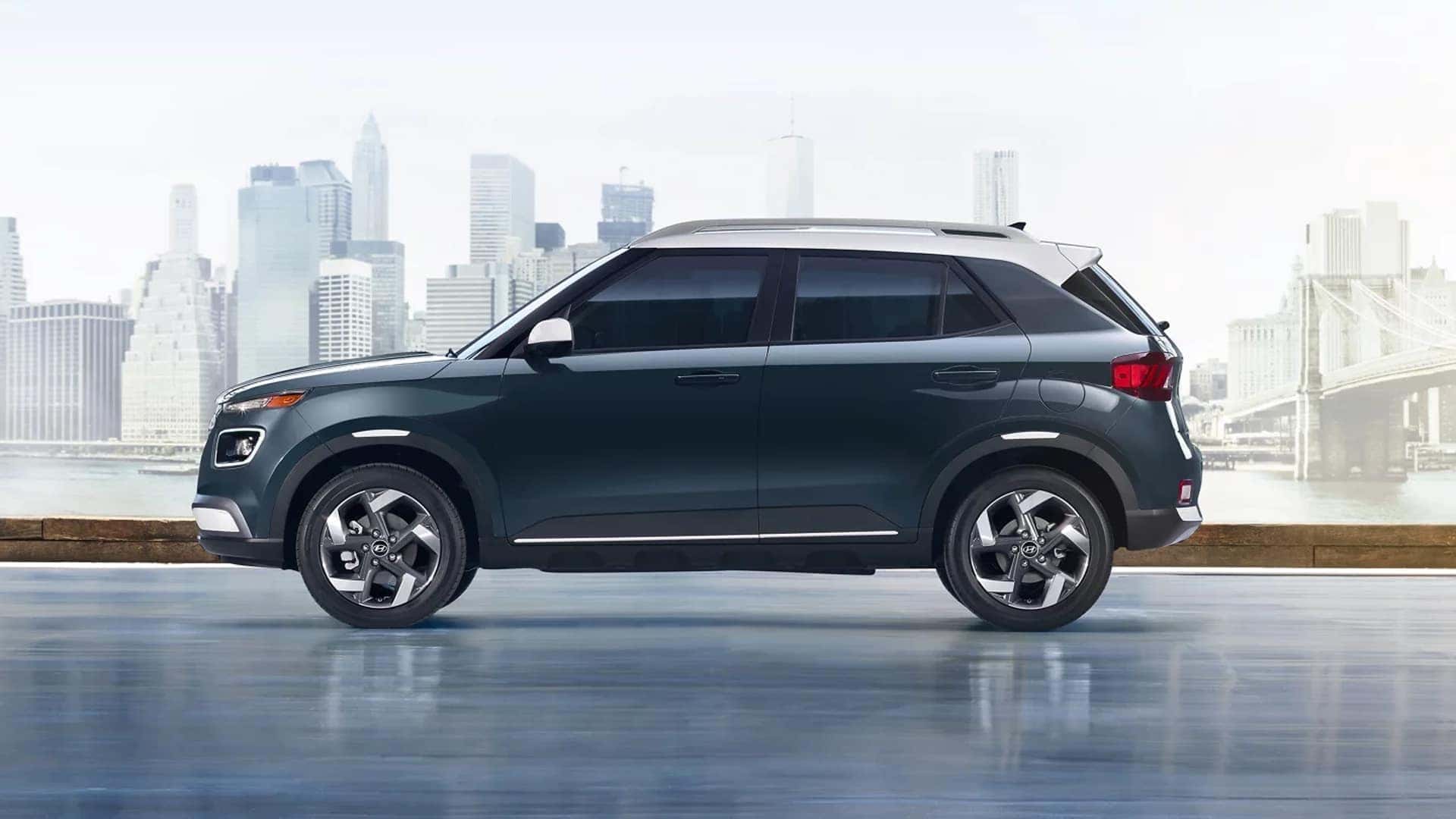 Side profile of a 2026 Hyundai Venue subcompact SUV with city skyline backdrop, showing compact proportions and wheel design