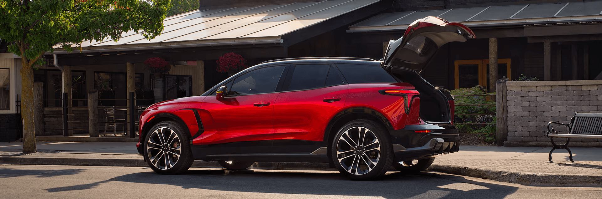 Red Chevy Blazer EV parked curbside with liftgate open, showing side profile and large wheels.