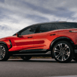 Red Chevy Blazer EV driving on open road, side profile with black roof, large alloy wheels, and LED lamps