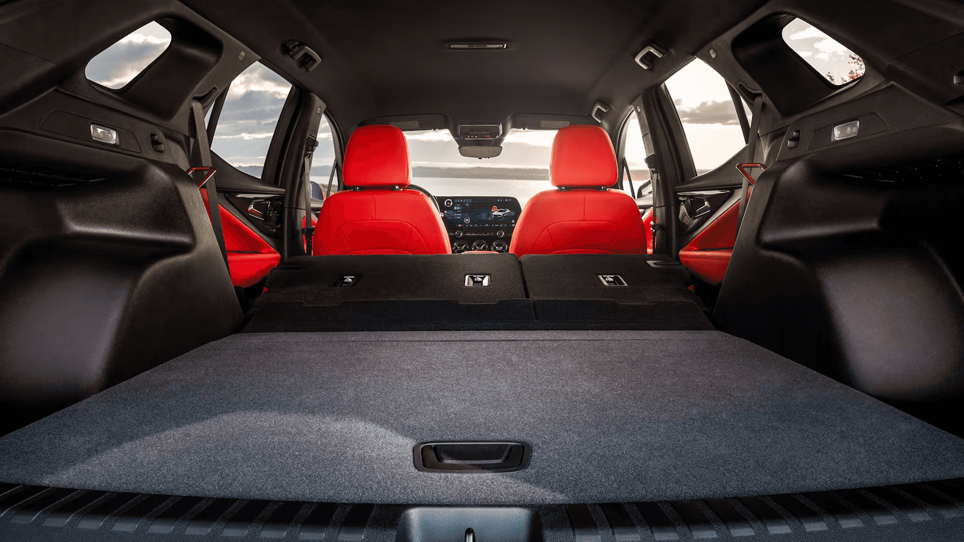 Cargo area view with rear seats folded flat, showing spacious load floor and red front seats in Blazer EV