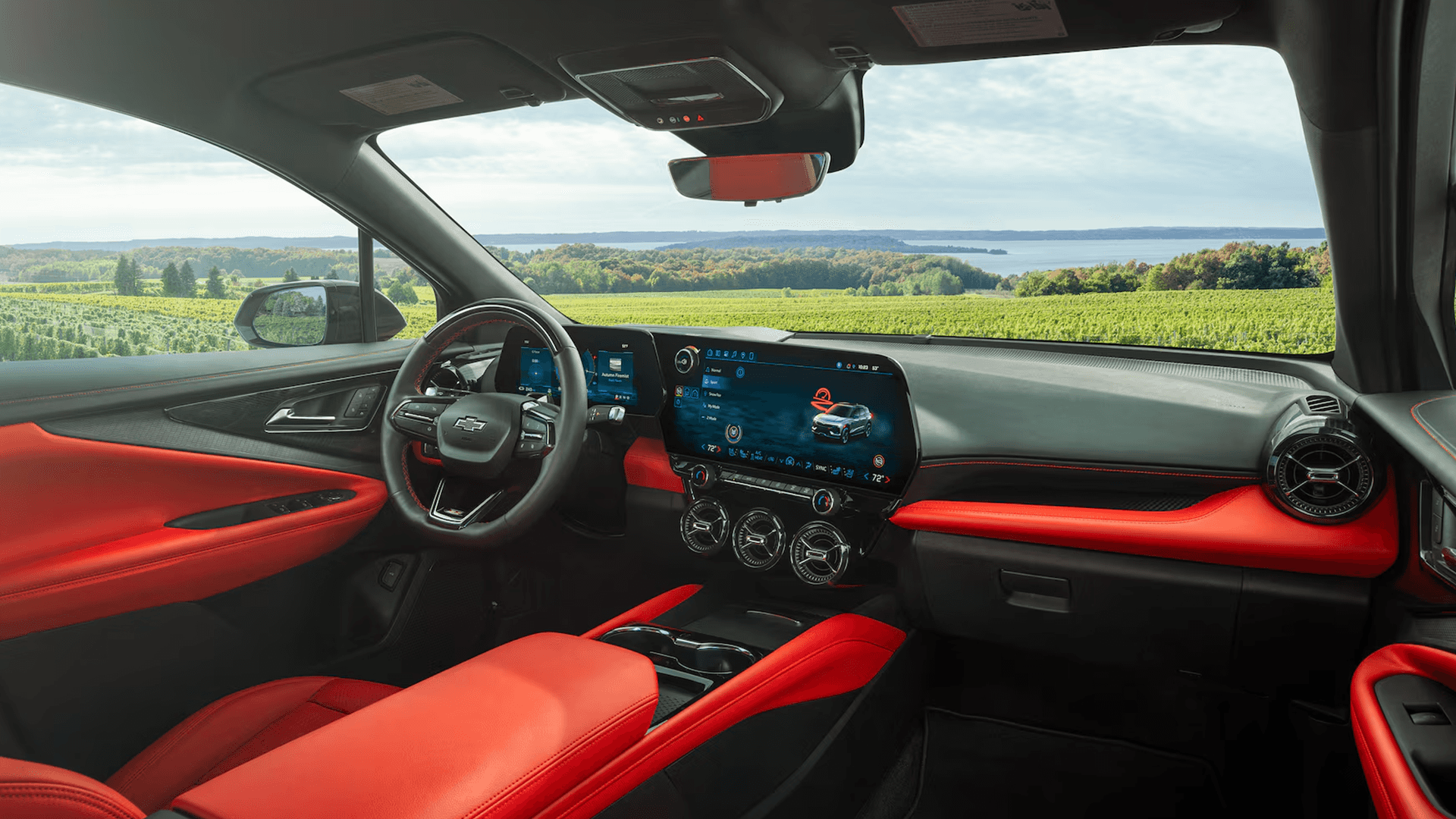 Front cabin overview of the 2026 Chevy Blazer EV highlighting steering wheel, center touchscreen, and sporty red trim