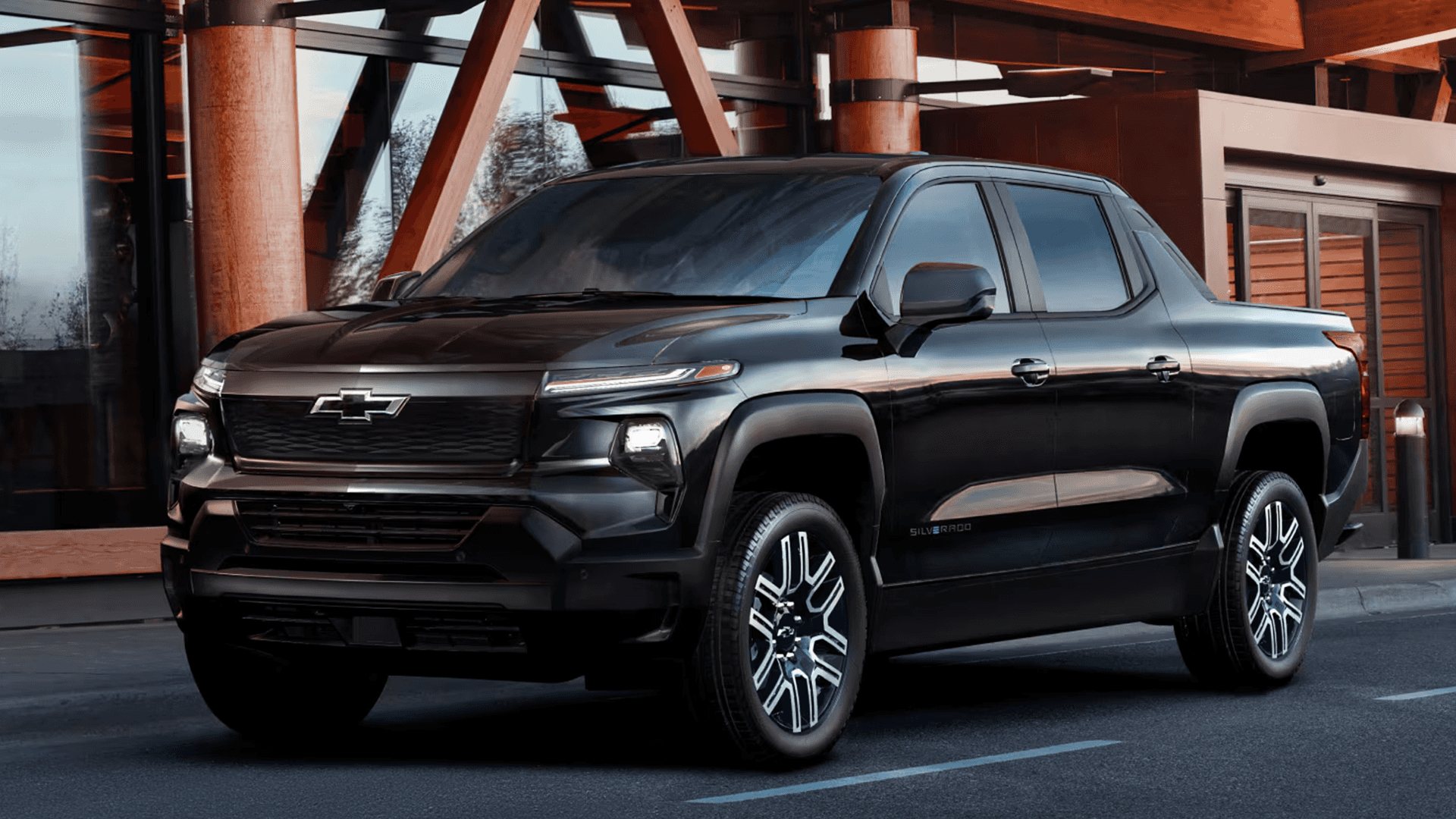 Black 2026 Chevy Silverado EV parked outside a modern building, front three quarter view in city setting