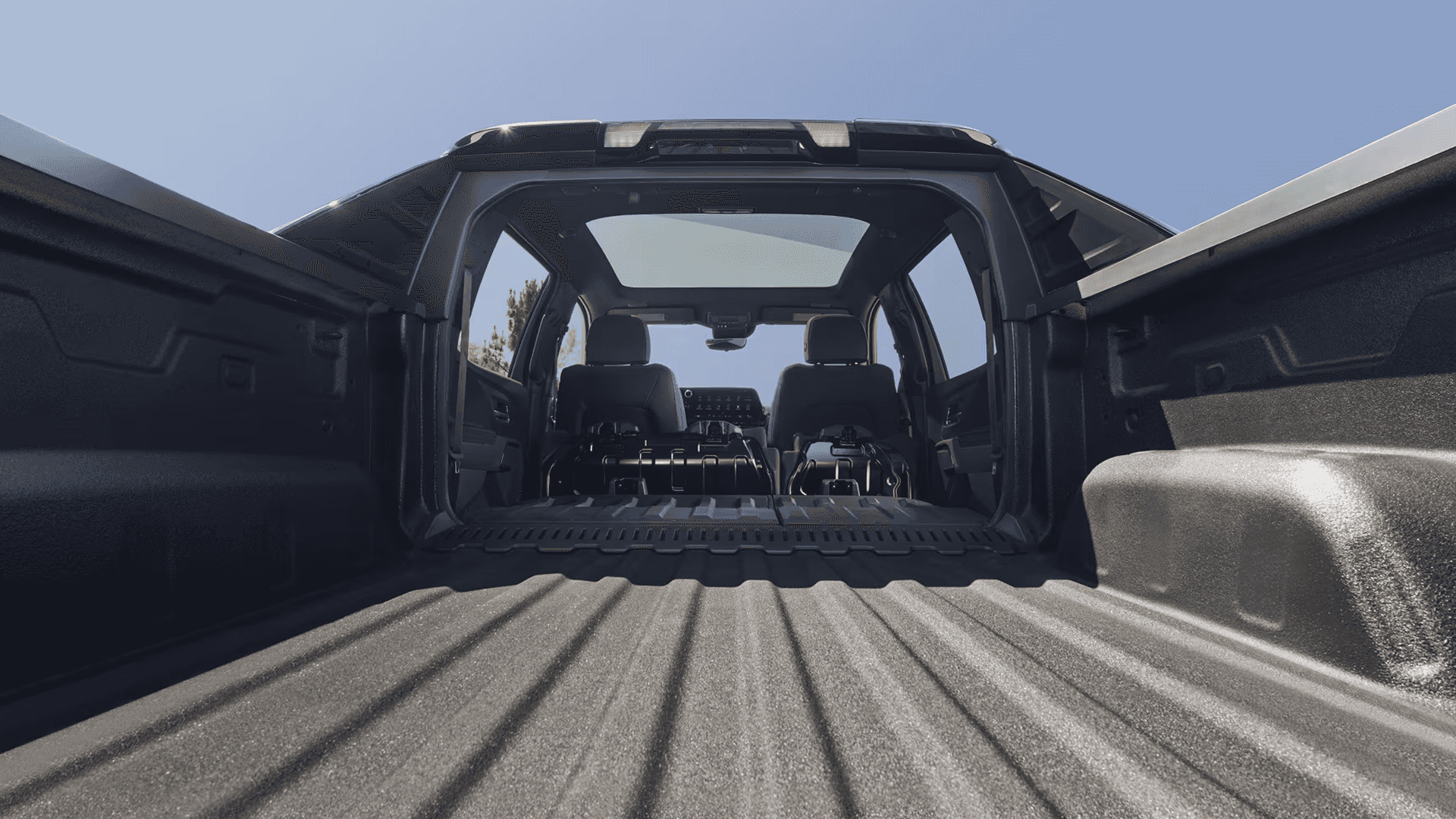 View from inside the Silverado EV bed looking into the cab with the midgate open and cargo floor extended.