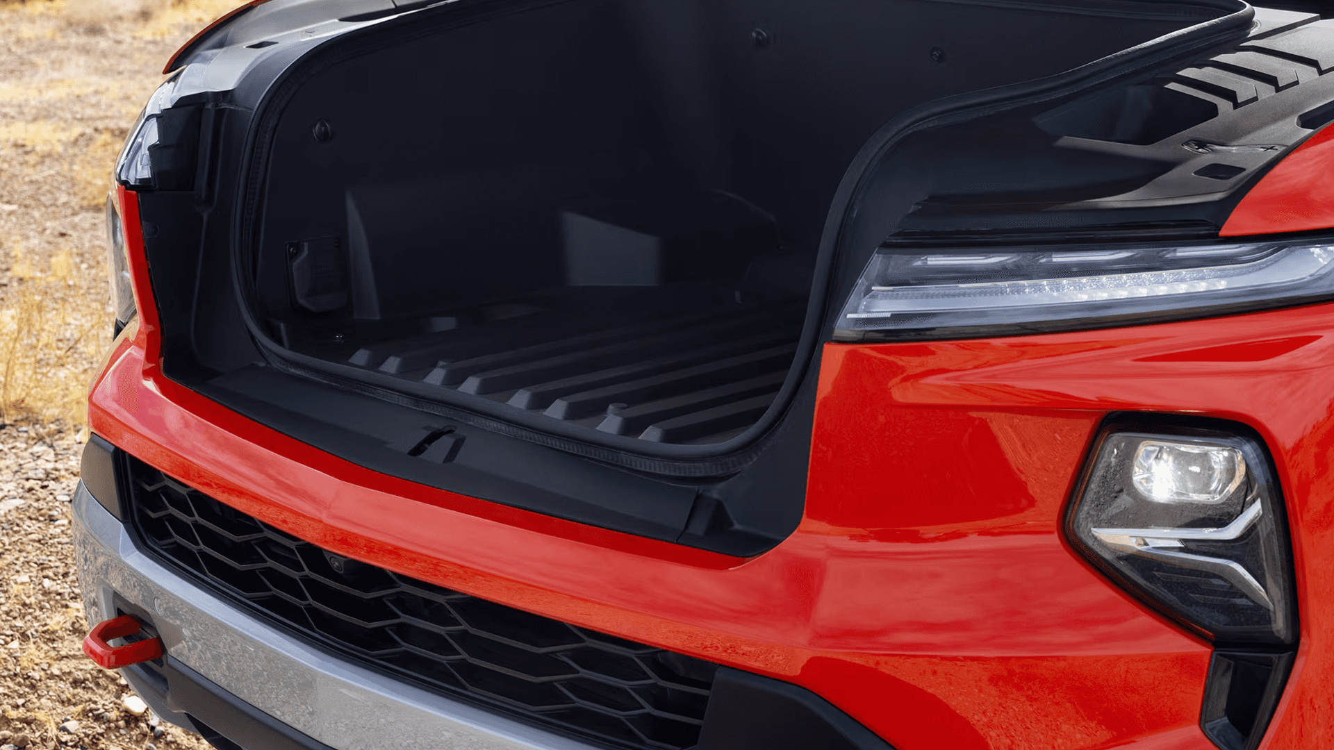 Close up of a red Chevy Silverado EV with the front eTrunk open, showing the front cargo storage area.