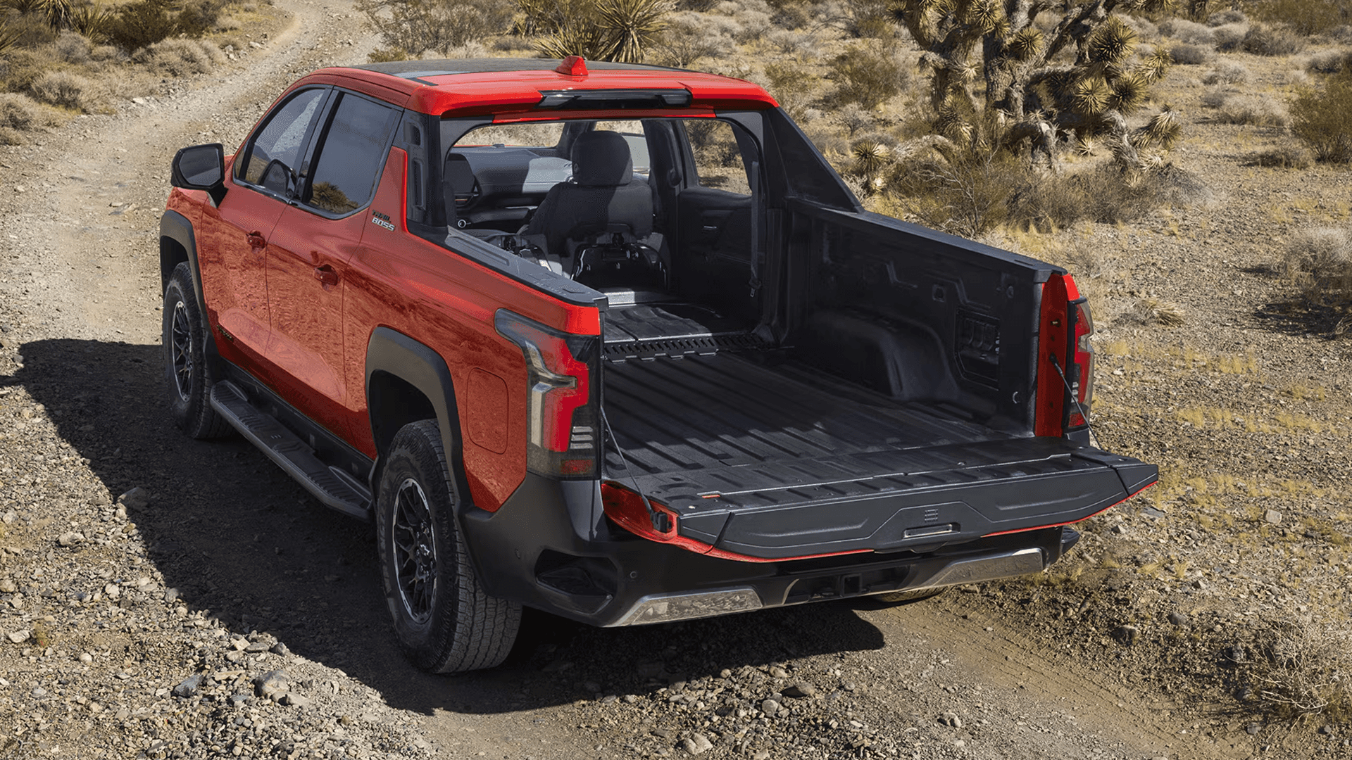 Red Silverado EV with tailgate down and midgate pass-through open, showing extended cargo space in bed