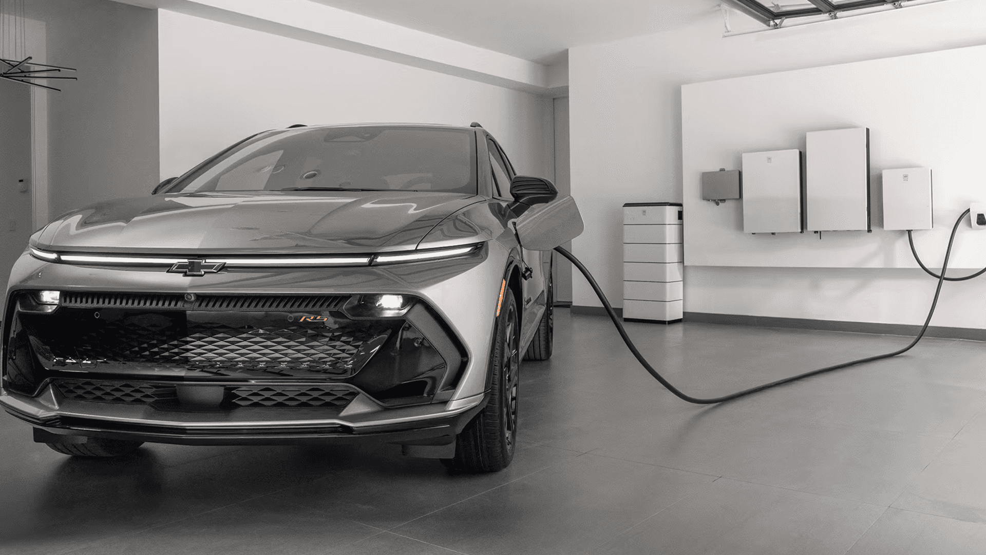 Gray 2026 Chevy Equinox EV charging in garage beside wall mounted home energy equipment and cables