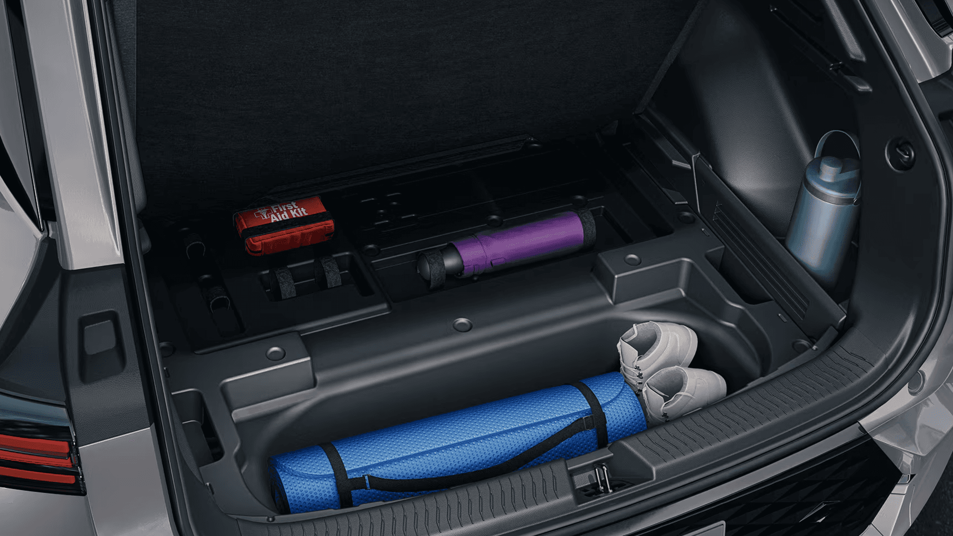 Underfloor cargo storage compartment in 2026 Equinox EV trunk holding a mat, shoes, bottle, and small gear