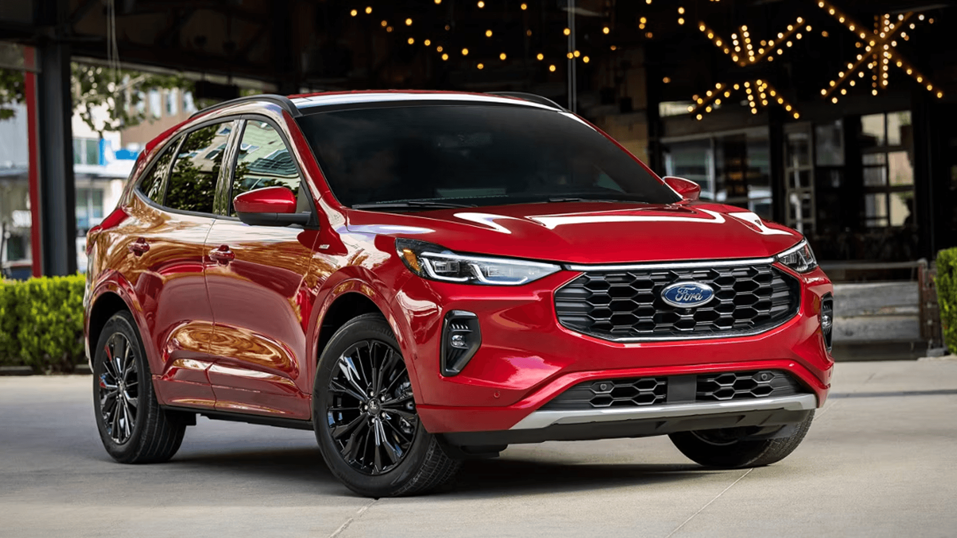Red 2026 Ford Escape angled front view at night, highlighting sporty stance, grille pattern, and black wheels.