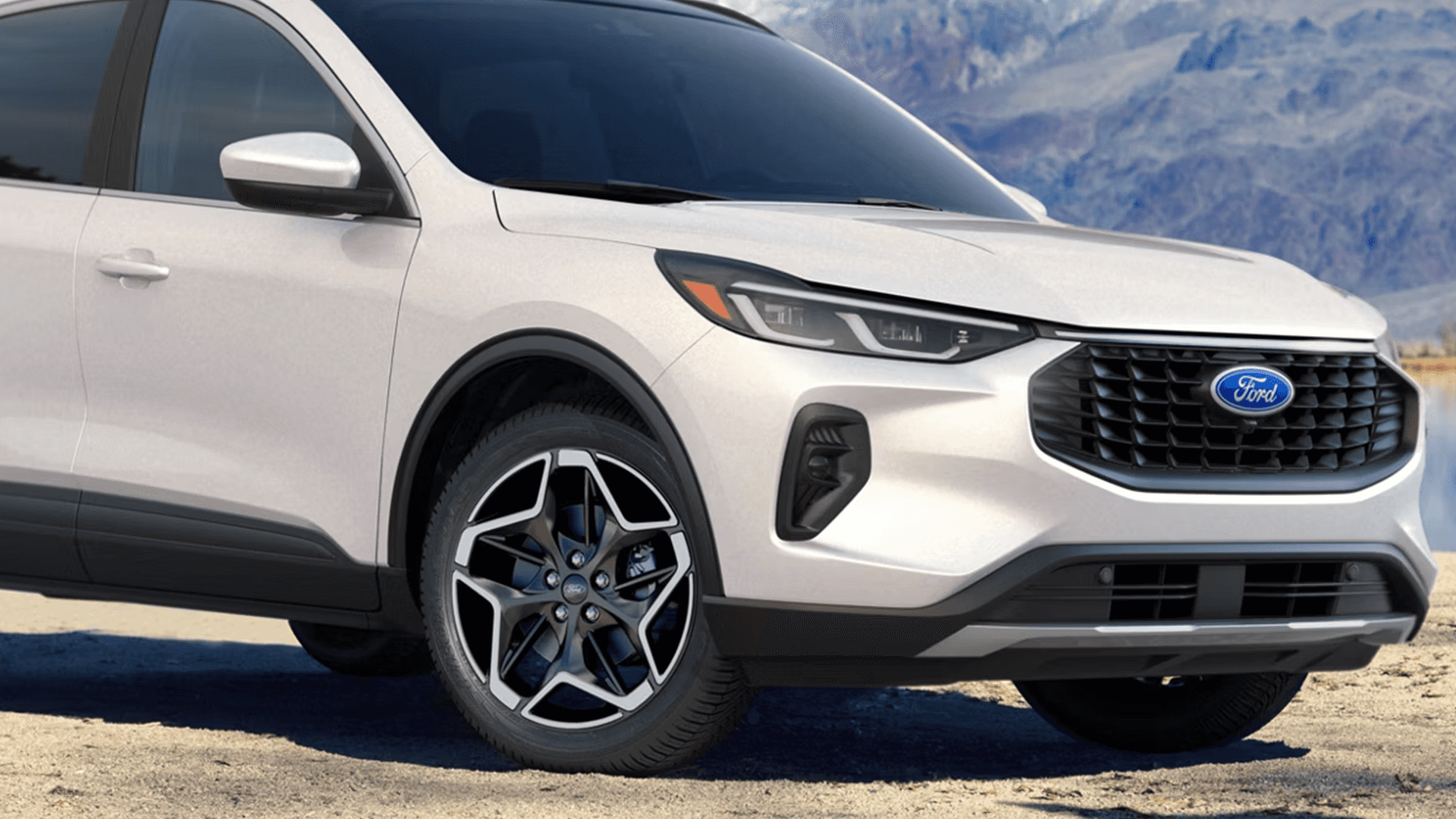 White 2026 Ford Escape front corner view showing alloy wheel design, grille, and slim headlamp styling.
