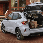 White 2026 Ford Escape with liftgate open at cabin, showing cargo area loaded with luggage and gear.