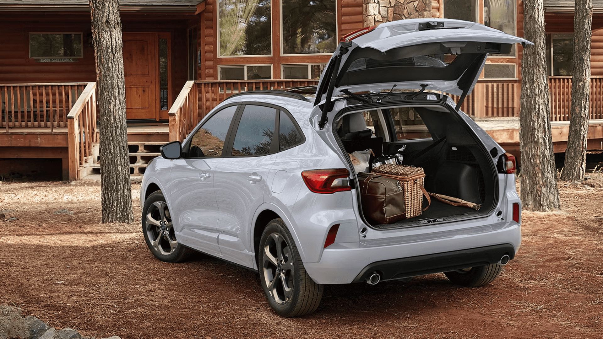 Silver 2026 Ford Escape with liftgate open at cabin, showing cargo area loaded with luggage and gear.