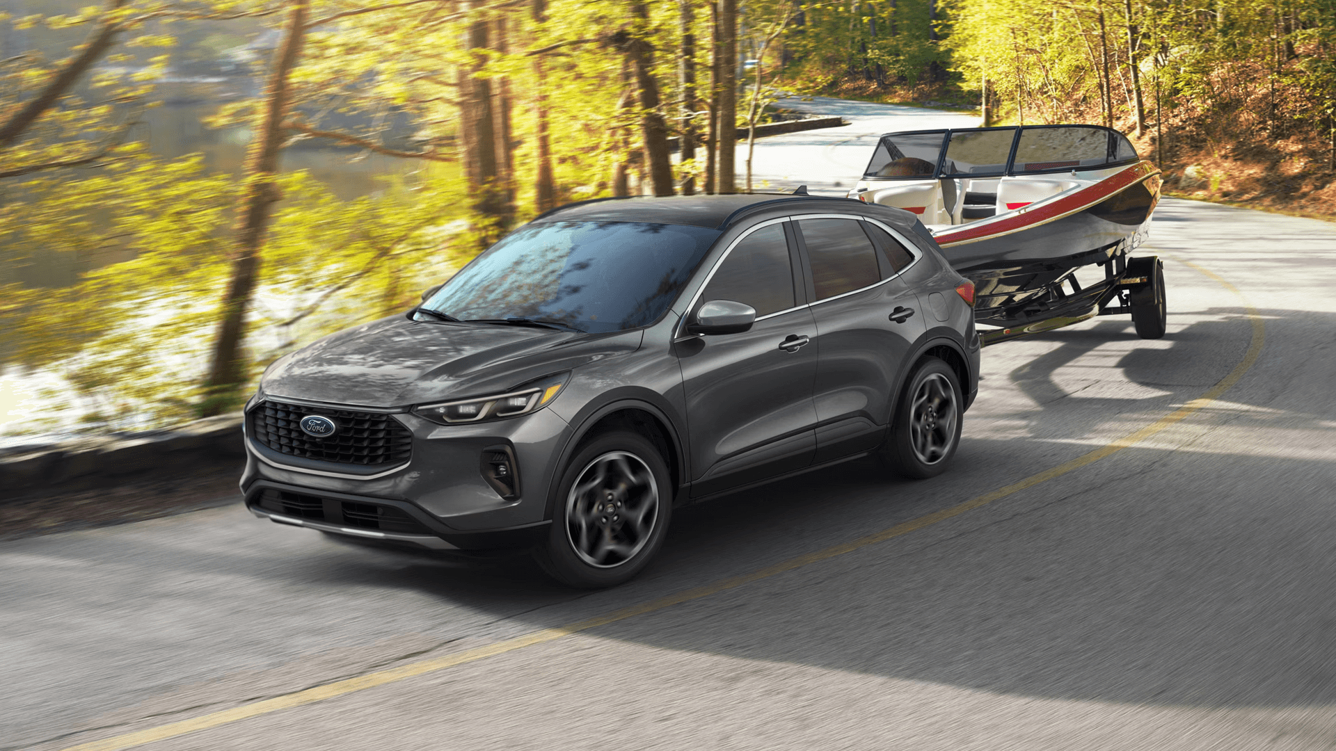 Gray 2026 Ford Escape towing a boat trailer on a winding lakeside road through sunlit trees