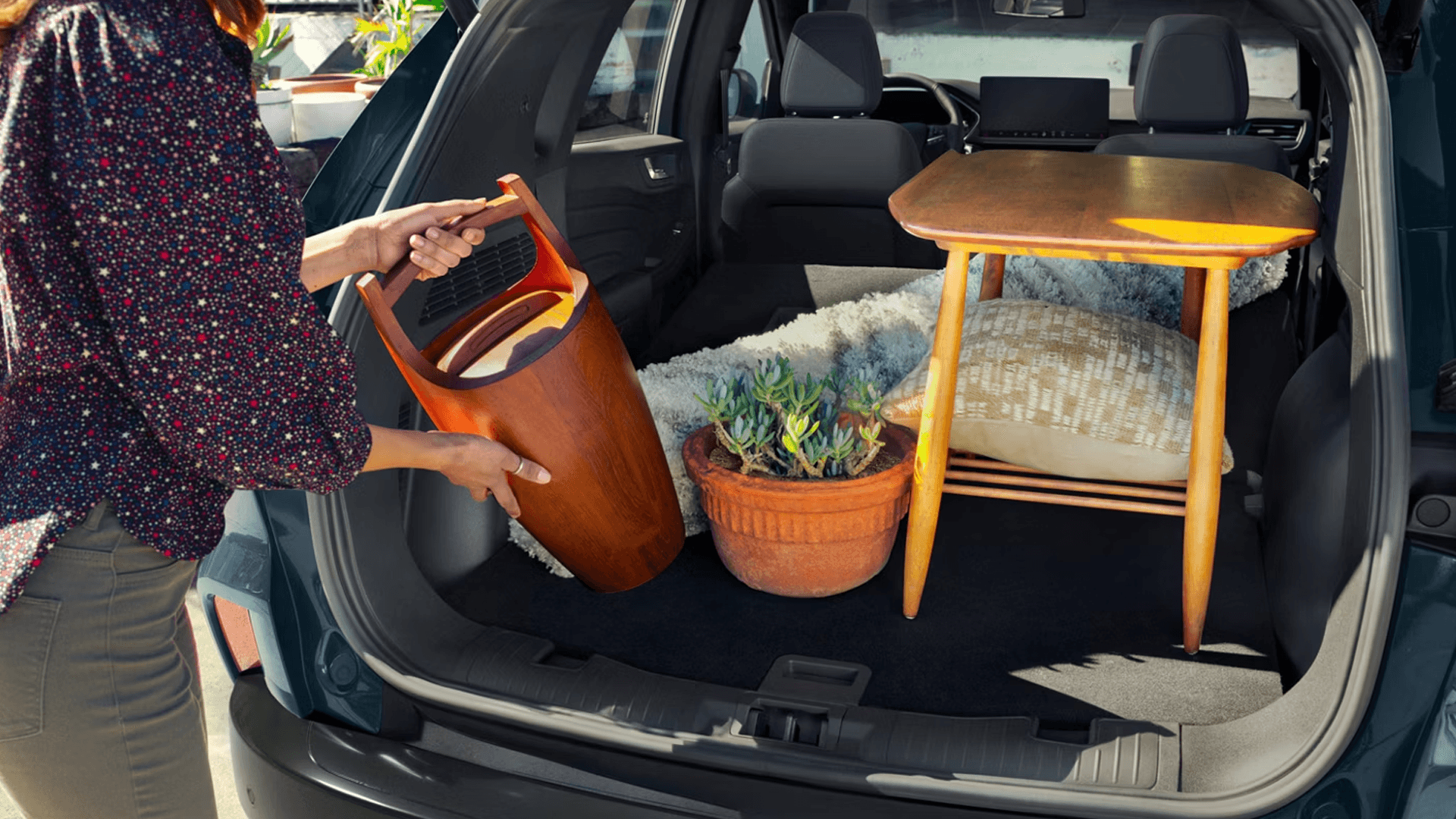 Person loading furniture and plant into open 2026 Ford Escape cargo area with rear seats folded flat