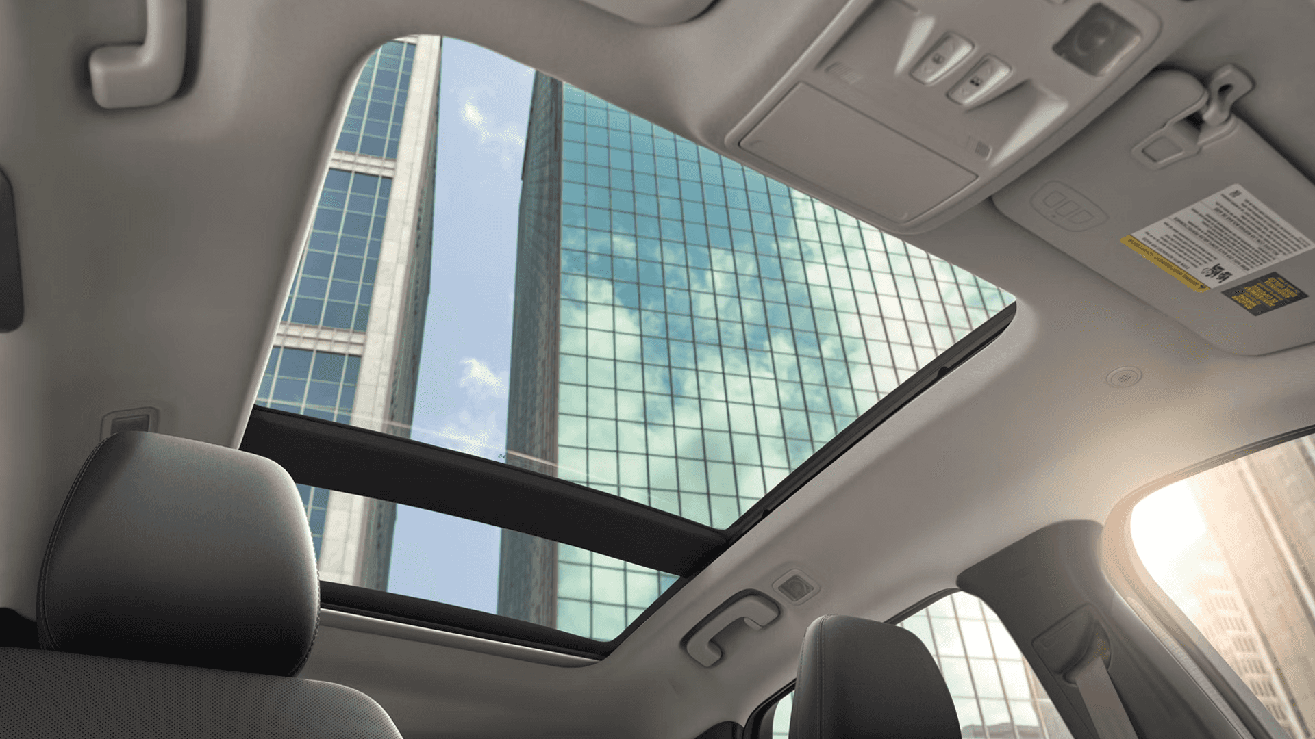 View through 2026 Ford Escape panoramic sunroof from rear seat with city skyscrapers and blue sky above