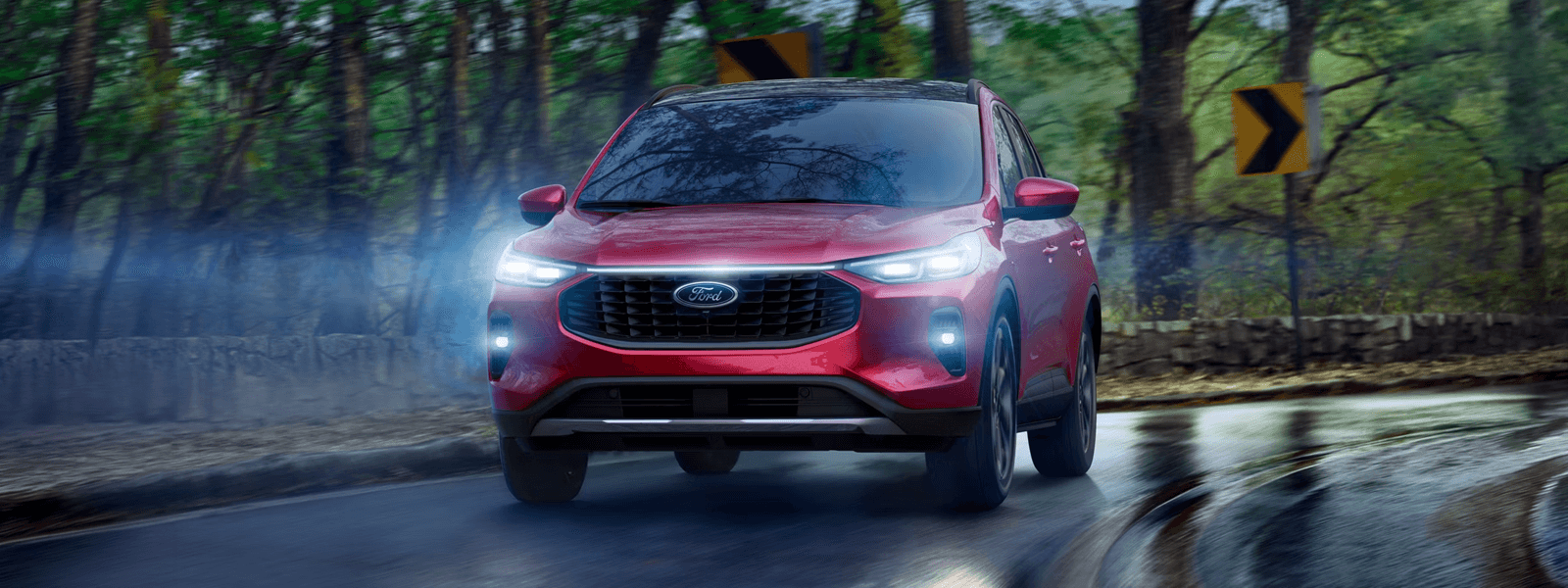 Red 2026 Ford Escape driving on a wet road with LED headlamps on