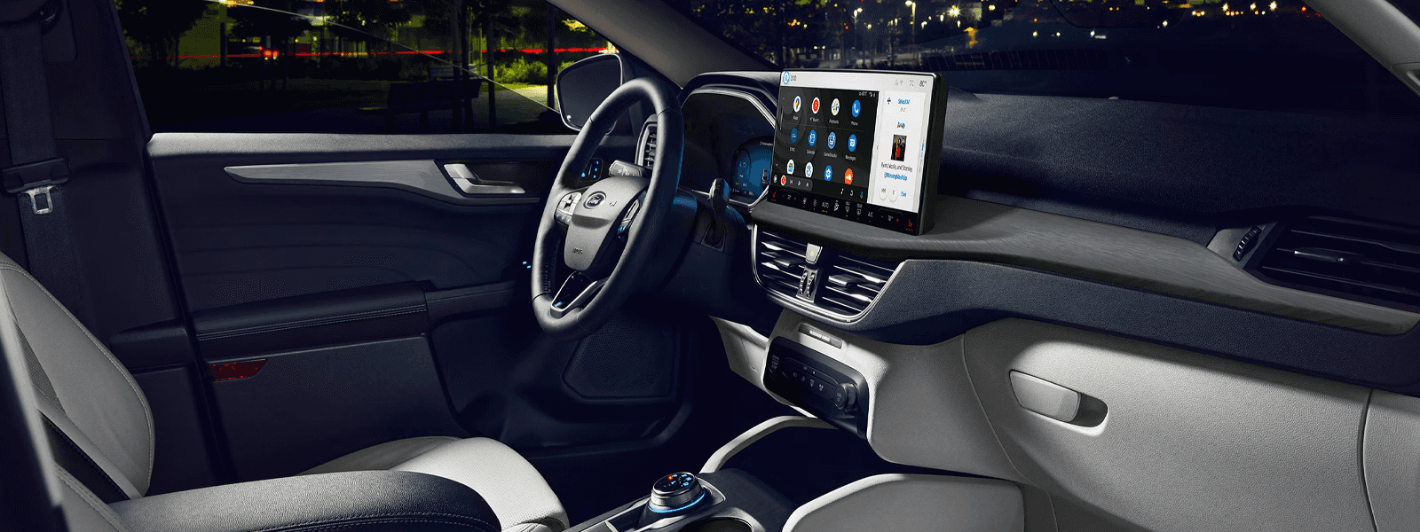 Night view of 2026 Ford Escape cockpit with large touchscreen, steering wheel, and rotary shifter