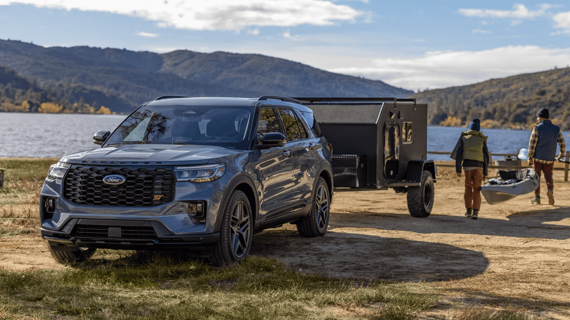 Ford Explorer ST towing compact camper near lakeside campsite, demonstrating trailering capability.