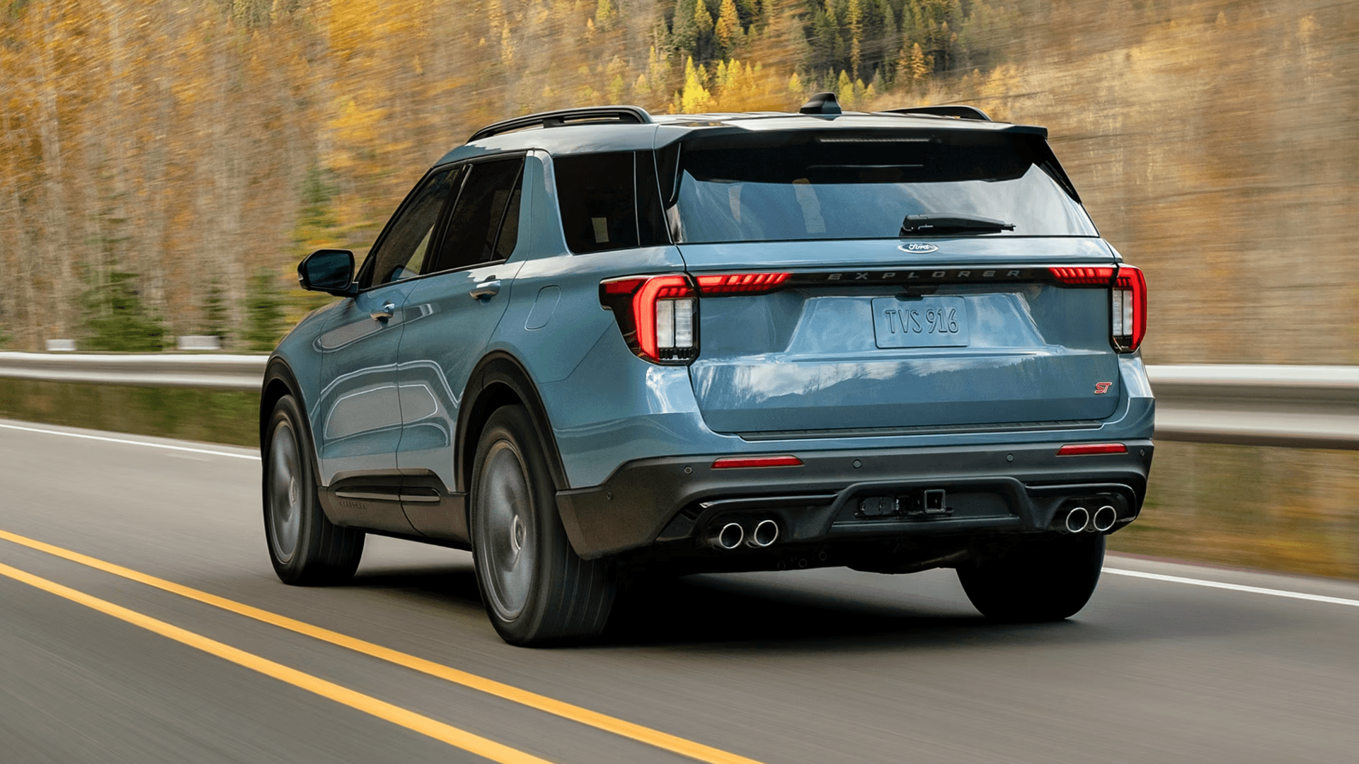 Rear three quarter view of blue Ford Explorer ST driving on highway, showing LED taillamps and dual exhaust