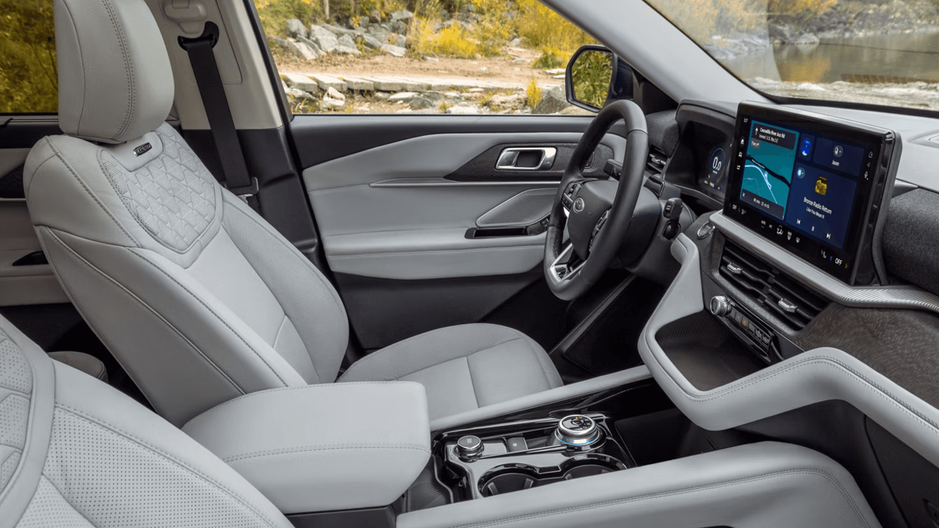 Front cabin of Ford Explorer with light seats, large touchscreen, digital cluster, and rotary gear selector