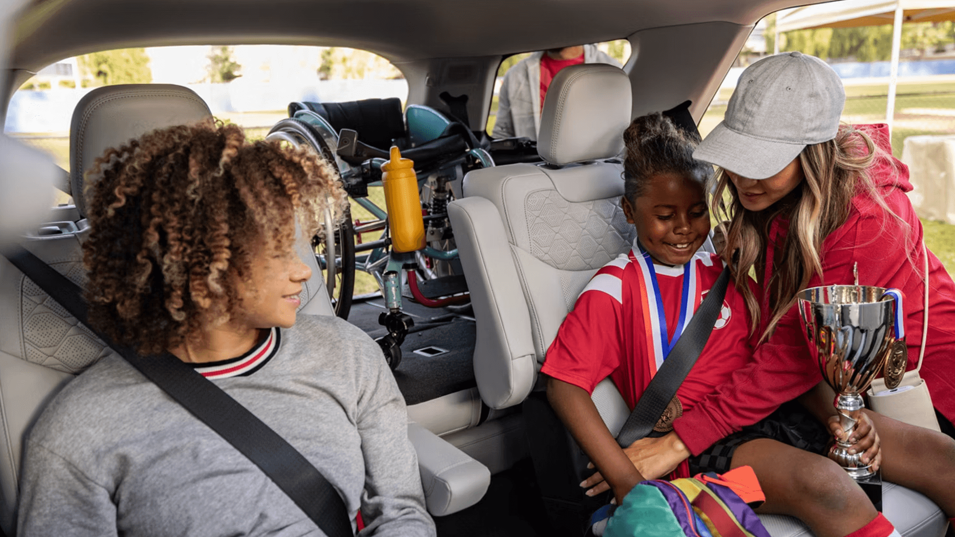 Family buckles child in Explorer second row with sports trophy and wheelchair stored behind, showing cargo space