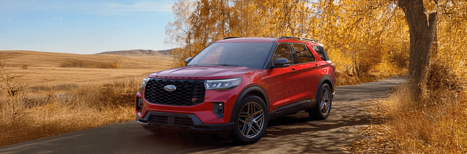 Red Ford Explorer ST parked on a country road with golden autumn trees and open prairie fields