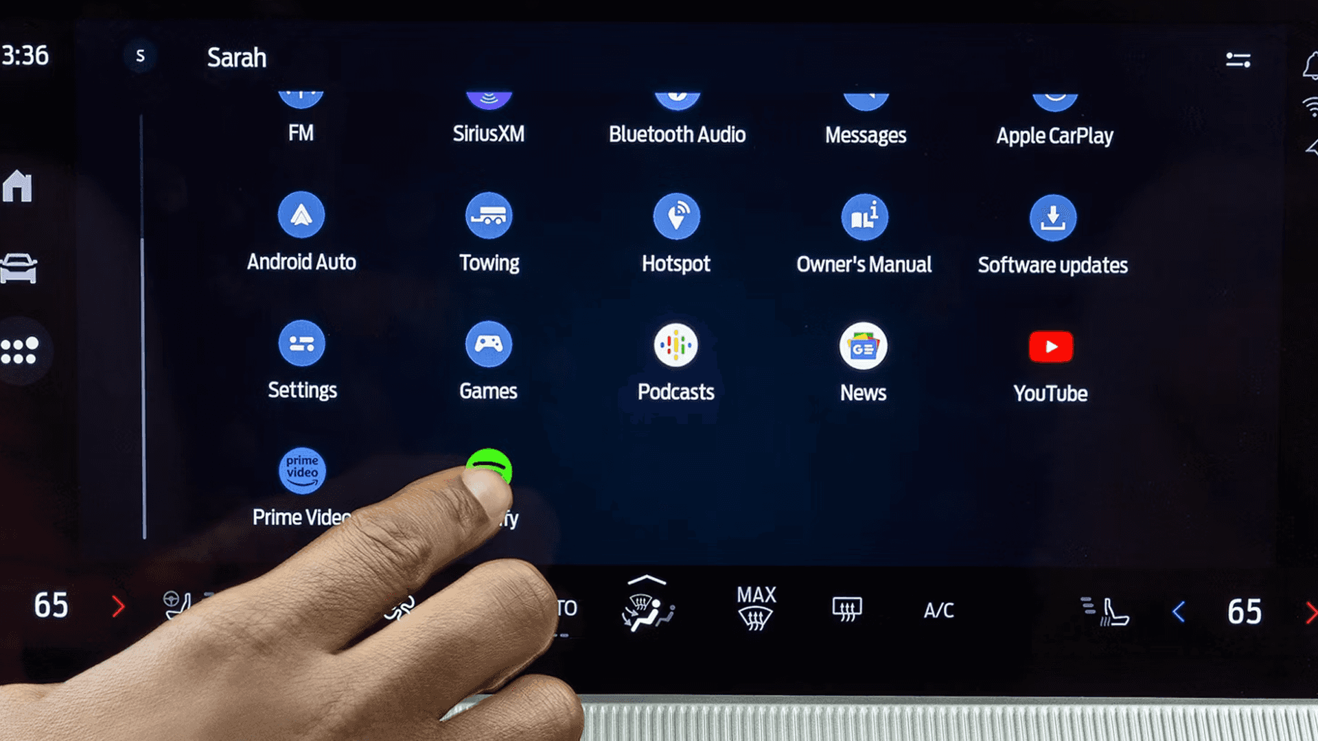 Close-up of 2026 Ford Explorer touchscreen app grid with hand selecting Spotify and media icons
