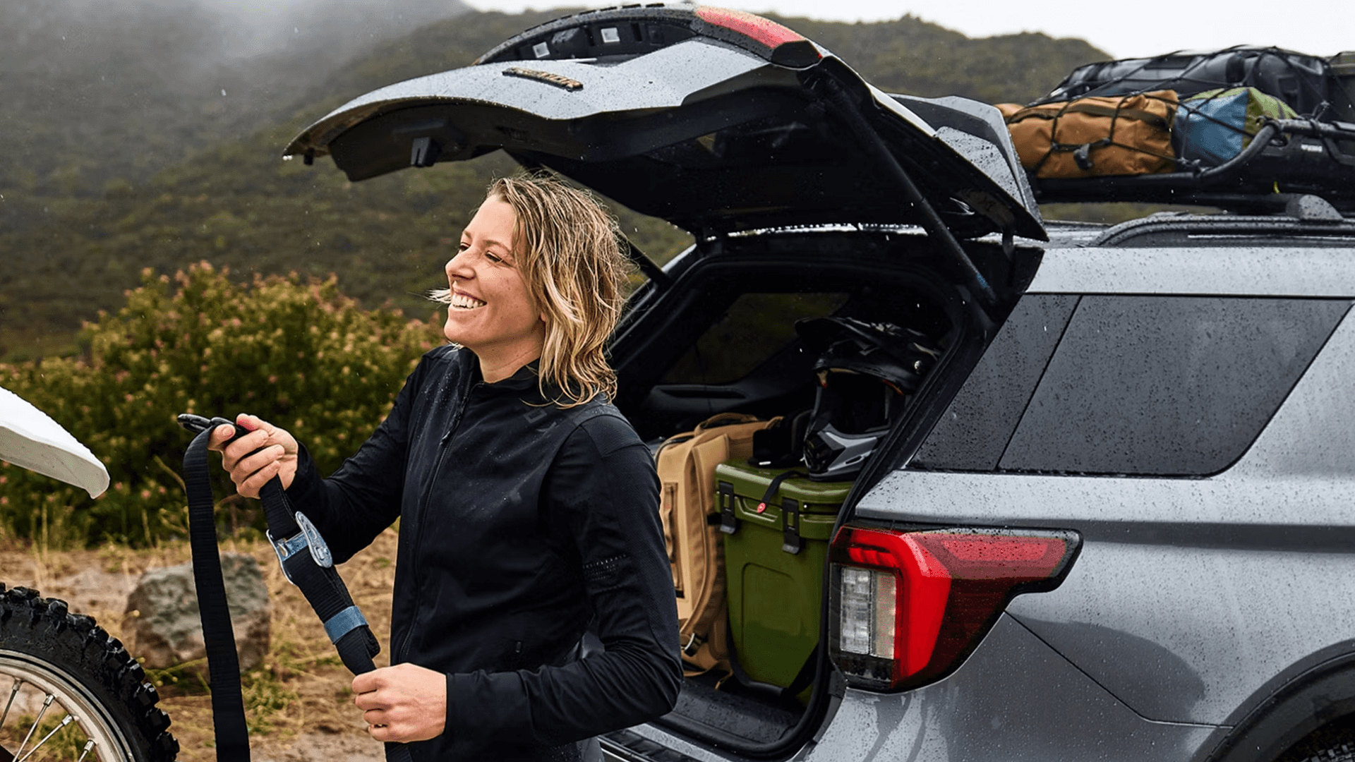 2026 Ford Explorer with liftgate open, showing packed cargo area while cyclist stands beside rear