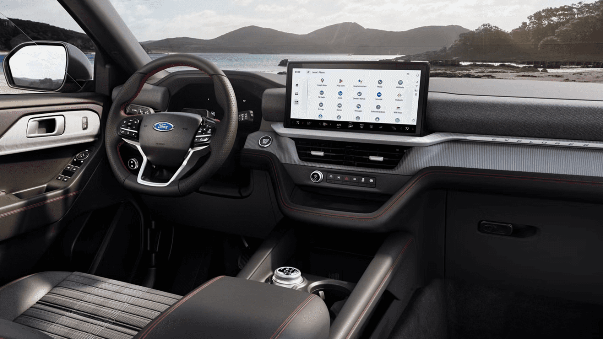 2026 Ford Explorer dashboard with wide center touchscreen app grid and steering wheel against scenic backdrop