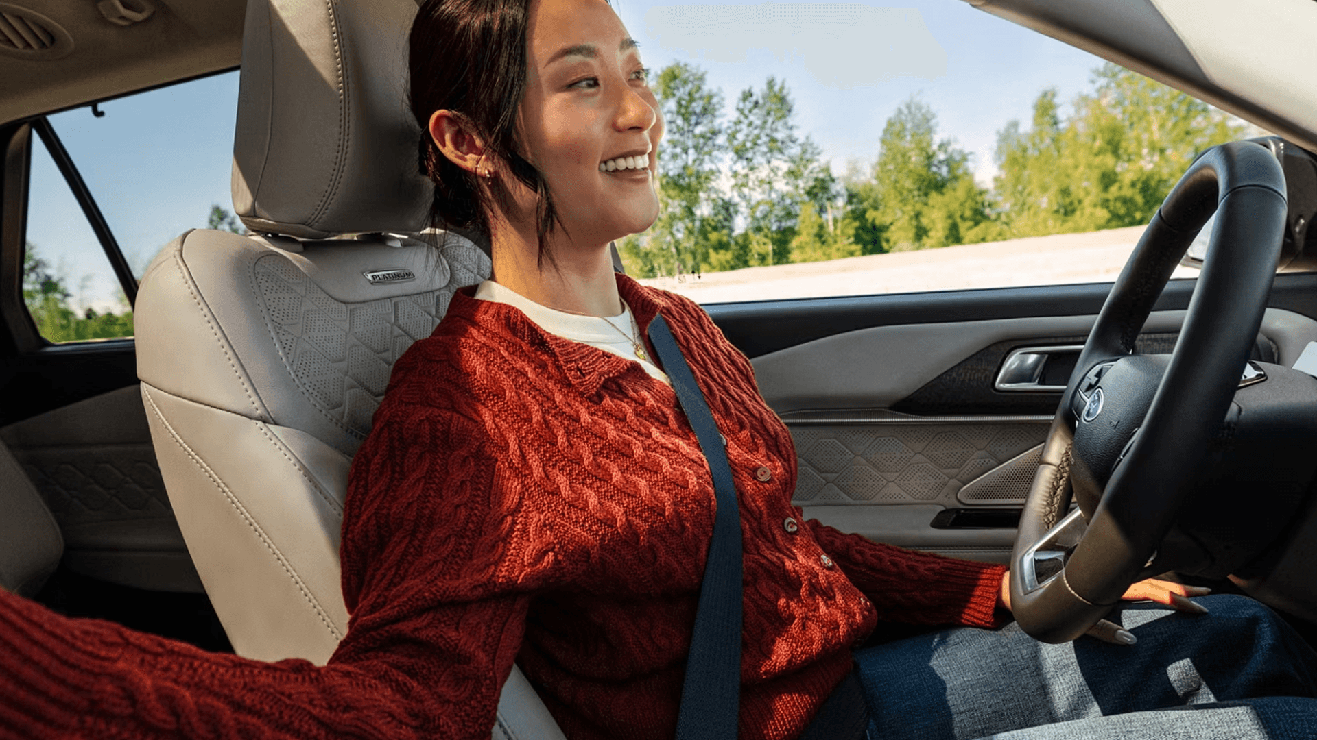Driver smiling with hands off wheel in 2026 Ford Explorer using available BlueCruise on highway