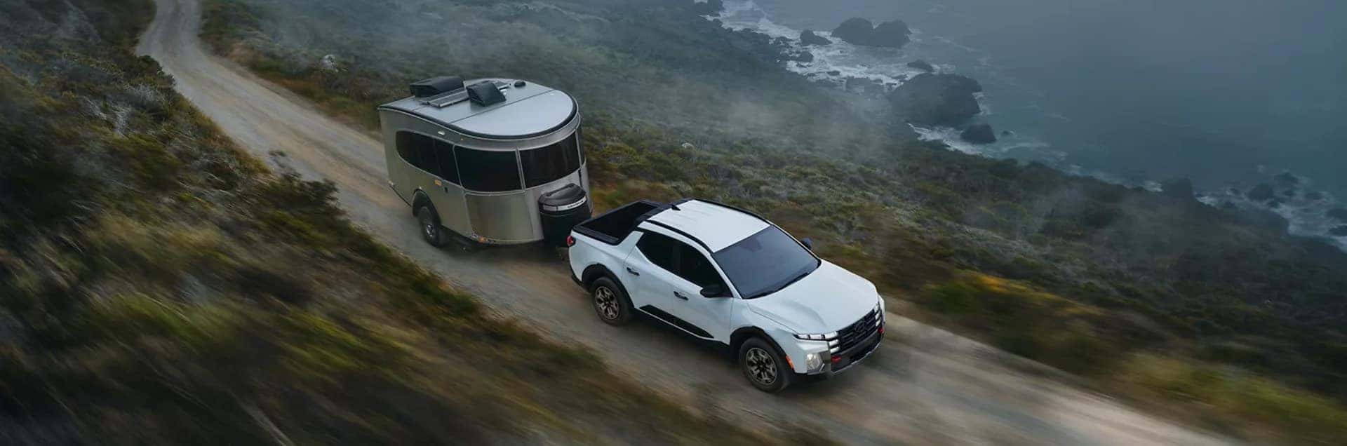 2026 Hyundai Palisade Hybrid driving on a bridge next to a Hyundai hybrid sedan, showcasing fuel efficiency and updated exterior design