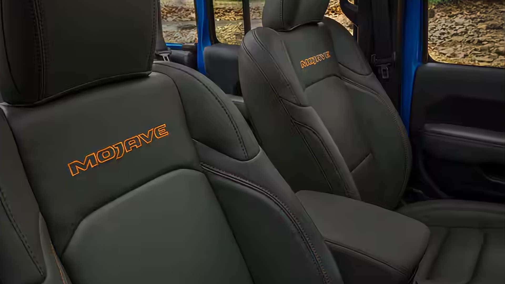 2026 Jeep Gladiator Mojave interior showing embroidered front seats, bolstered cushions, and open-air cabin