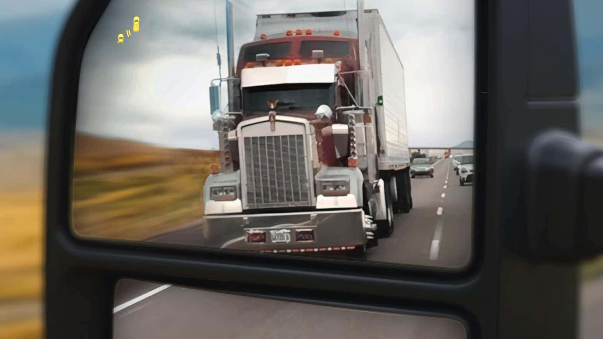 Side mirror view in 2026 Ford F-250 Super Duty showing Blind Spot Information System alert for nearby semi truck